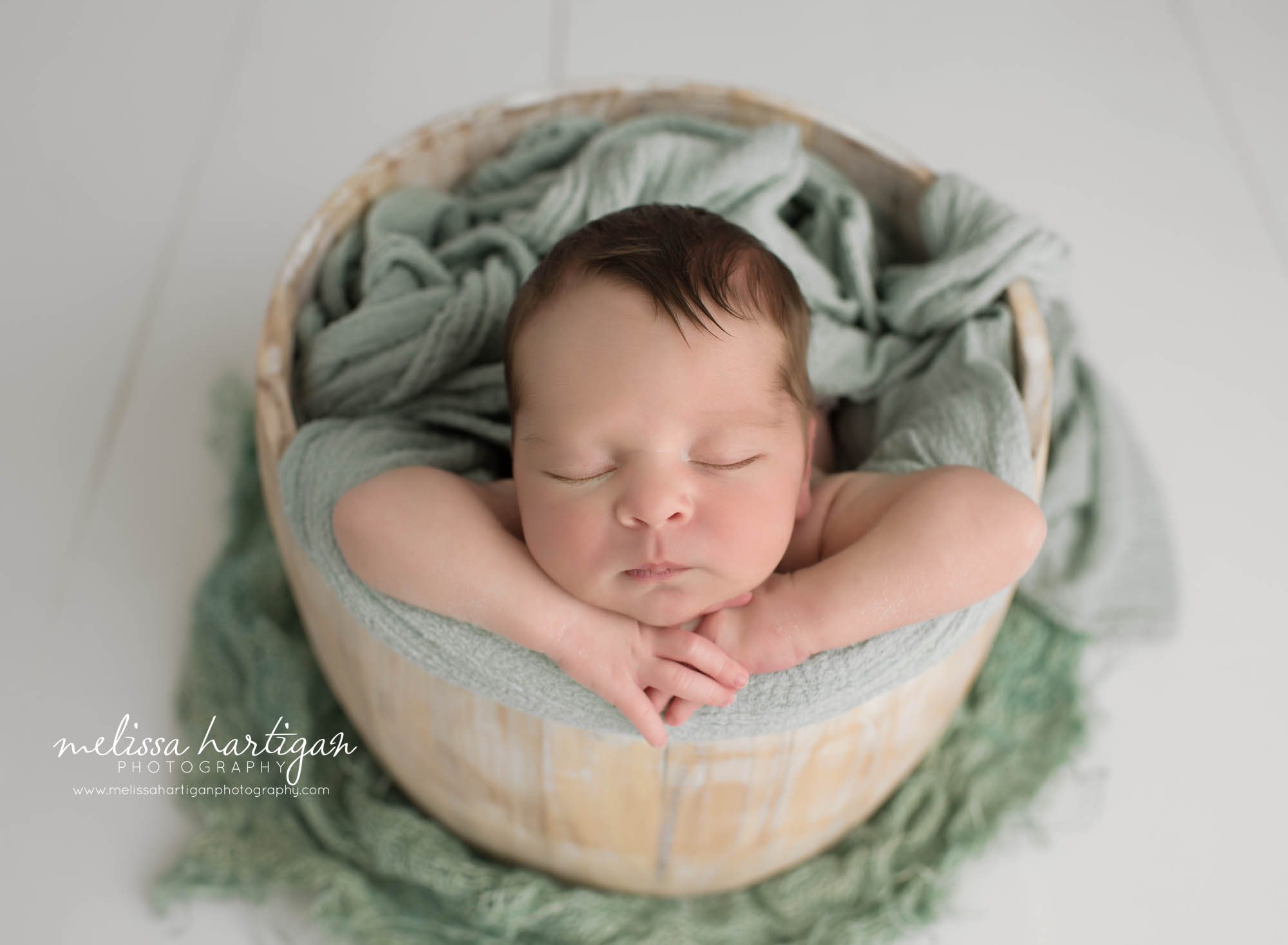 baby boy posed in wooden bucket with mint green layer wrap