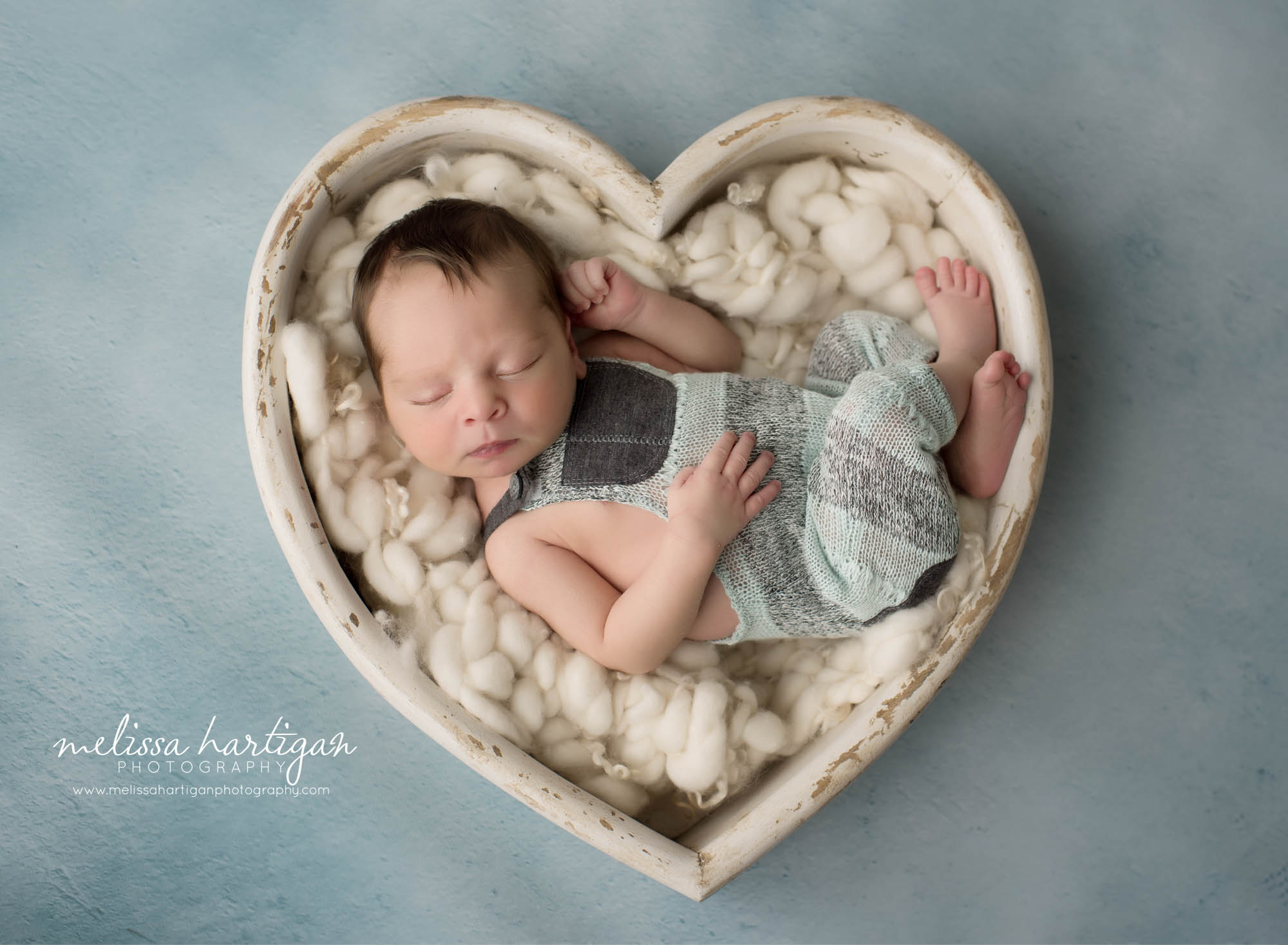 baby boy posed in white wooden heart prop over green backround CT newborn photographer