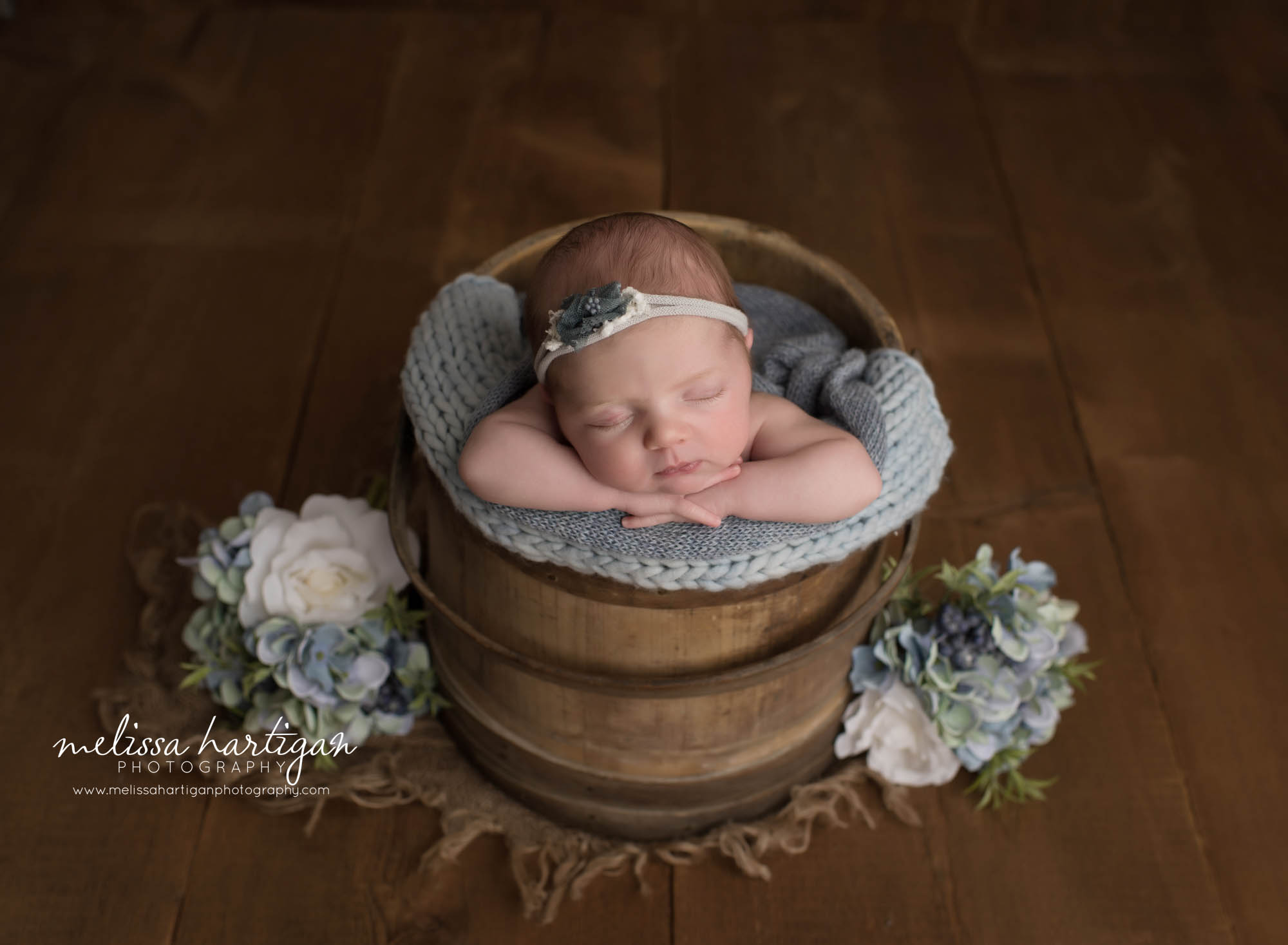 Newborn Baby girl posed in wooden bucket with light blue layers and blue flowers bsides bucket Connecticut Newborn Photography