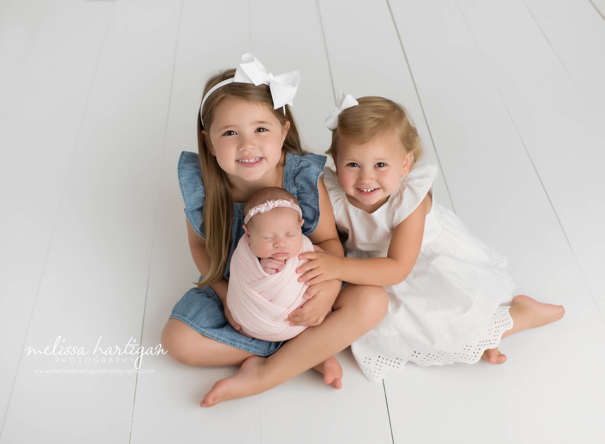 big sister and little sister holding newborn baby sister in sibling photo newborn photography CT