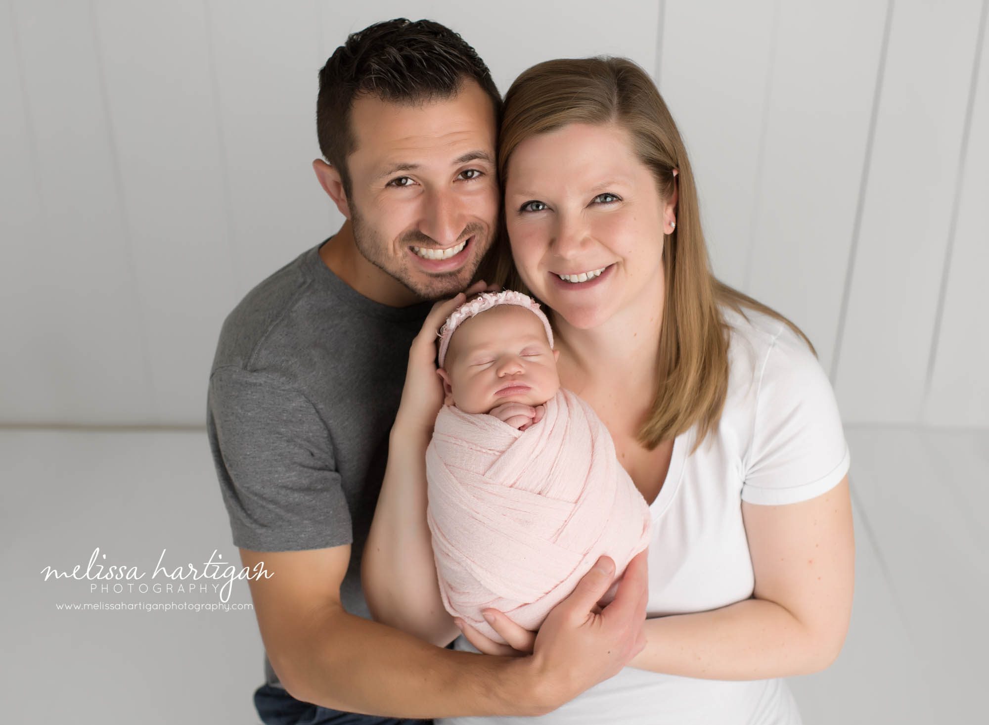 mom dad holding baby girl in family newborn session