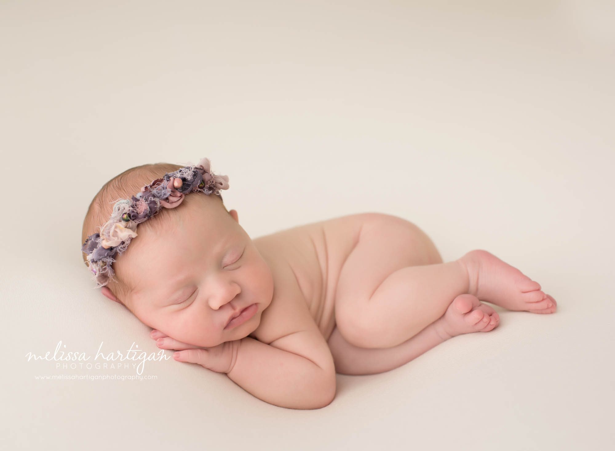 newborn baby girl pose don side with purple headband