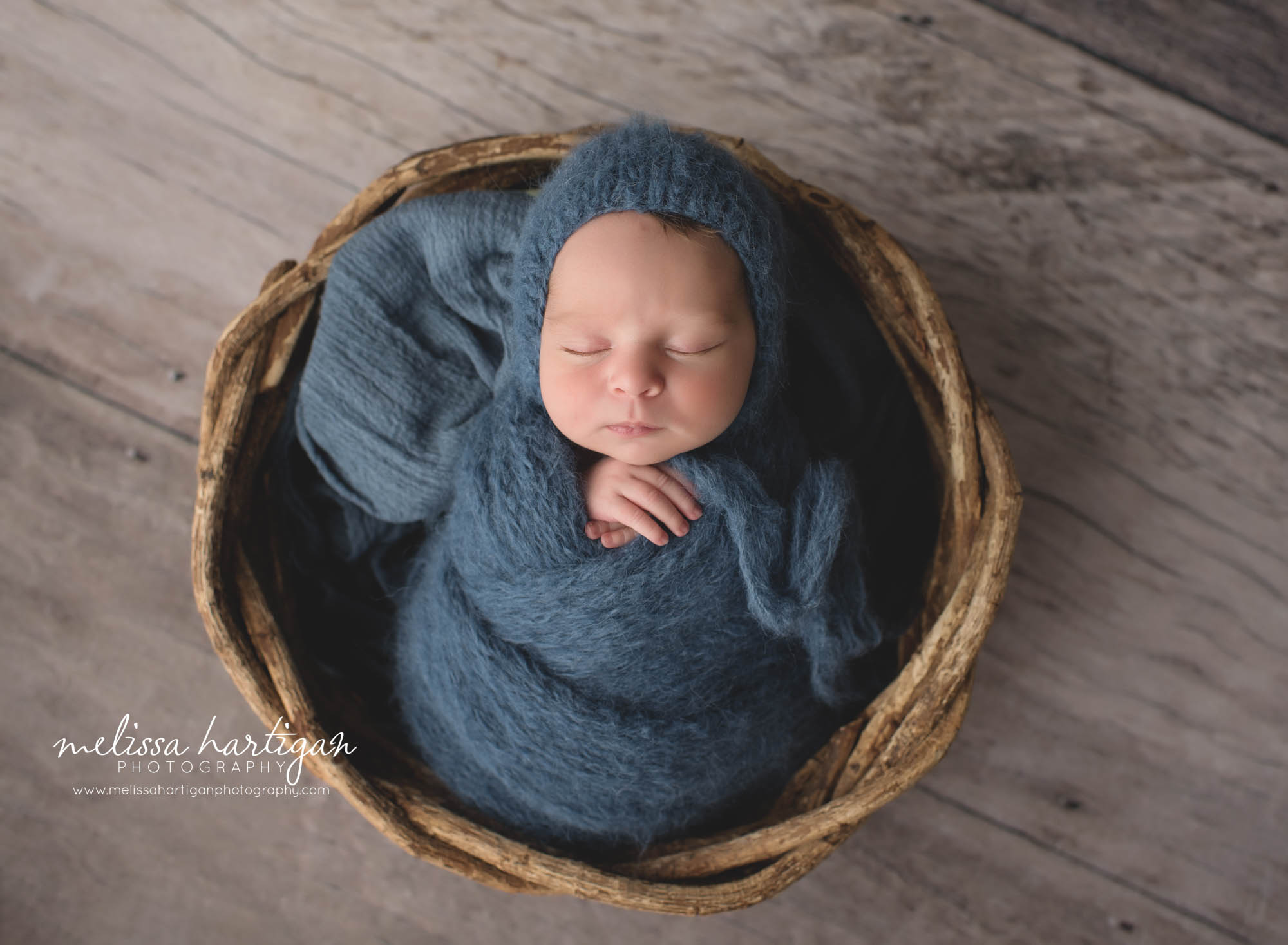 newborn baby boy posed in basket with navy blue