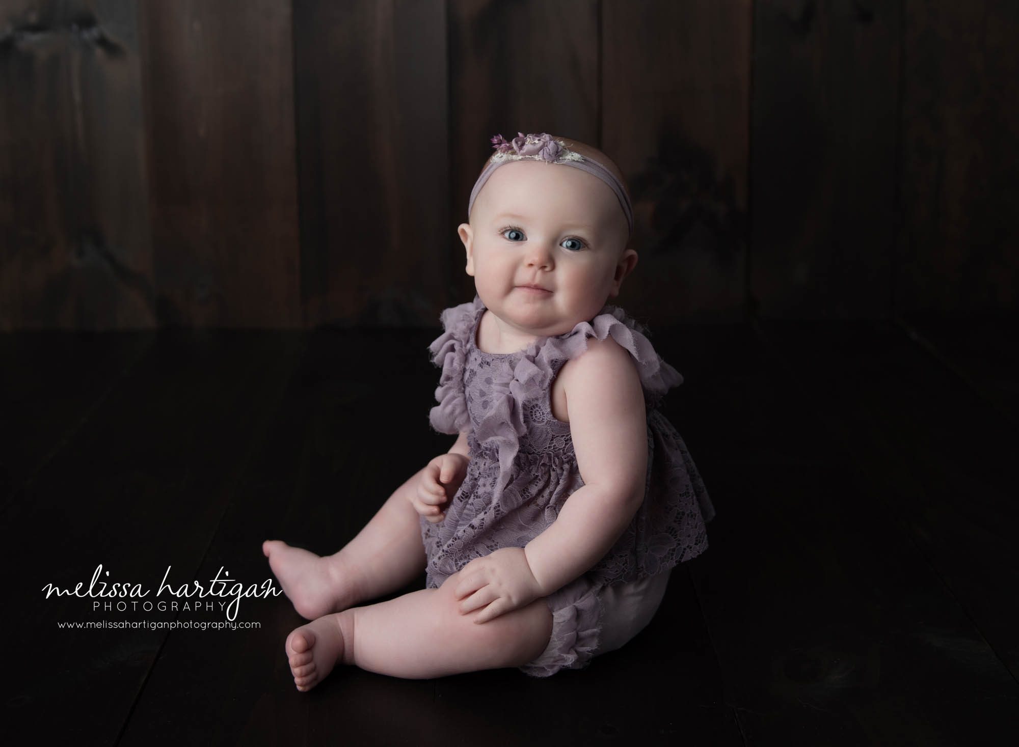 Baby girl sitting on wooden boards in CT Baby photography studio session capturing her sitting up unassistant baby milestone
