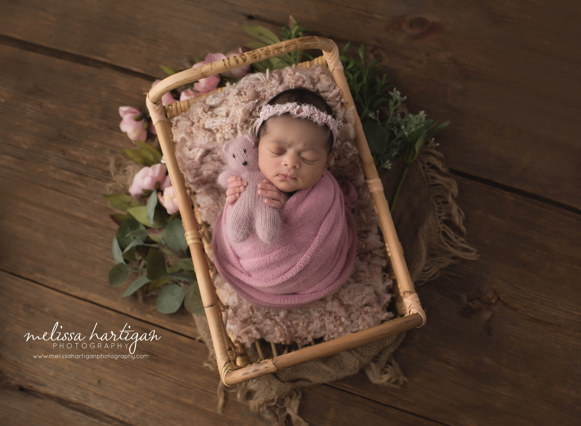 baby girl wrappe din pink posed in basket with flowers and greenery