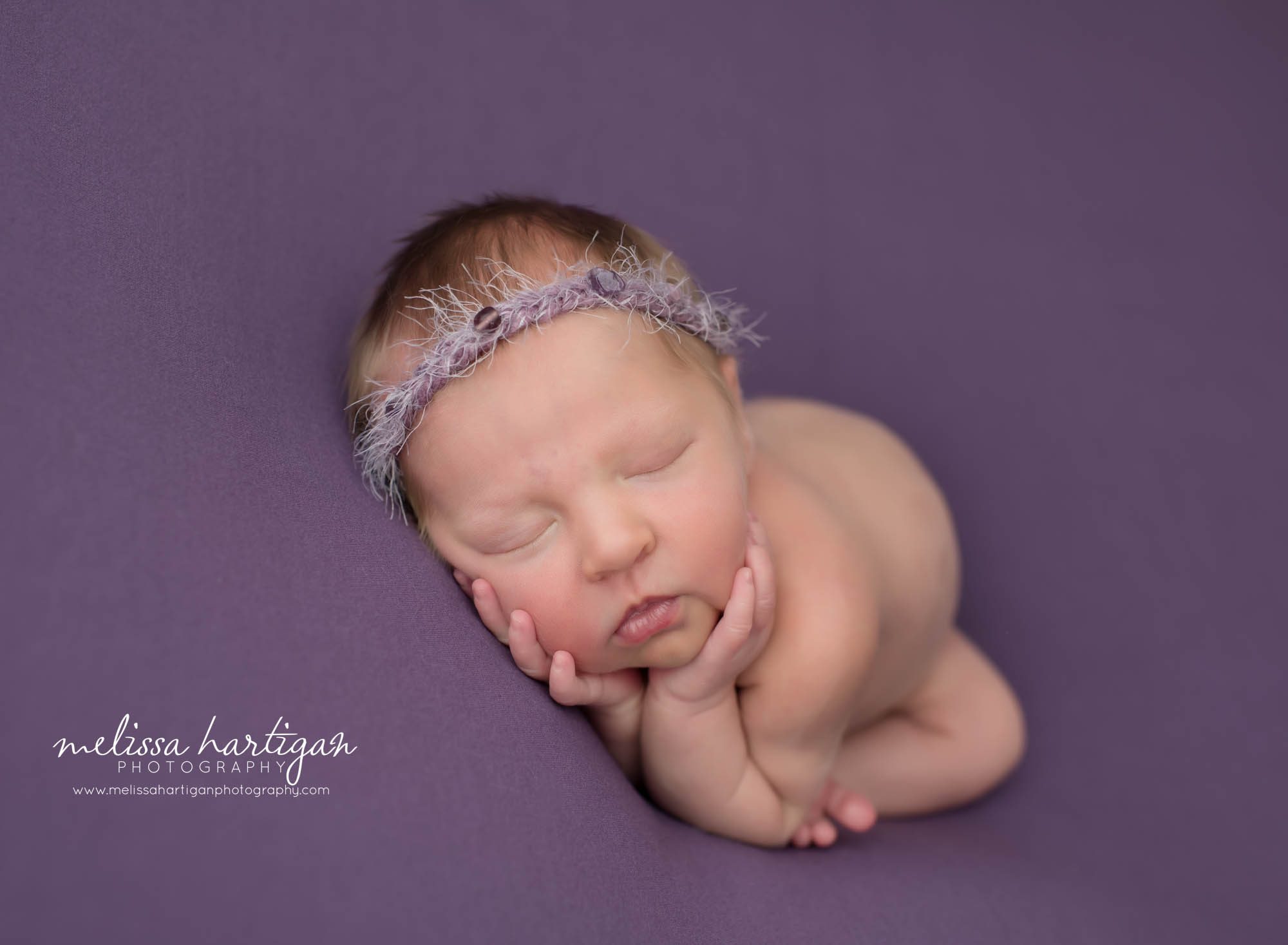 newborn baby girl posed with hands under chin on purple backdrop with purple headband CT newborn photography
