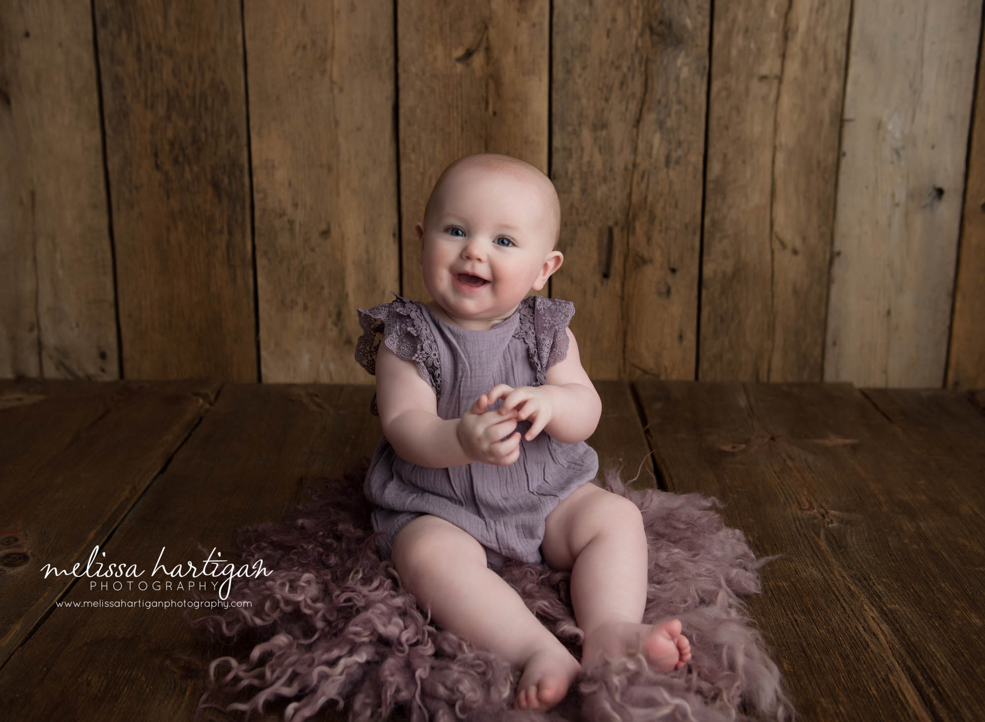 Baby girl sitting on purple curly fluff layer in CT baby photography studio session