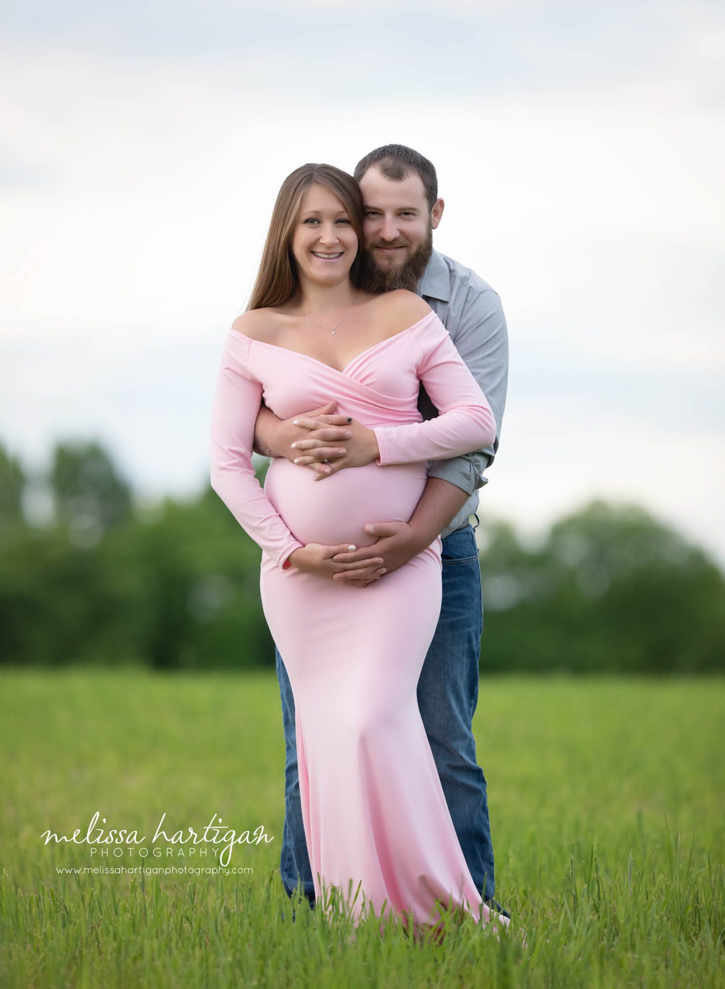 mom dad standing holding baby bump happy smiling at camera CT maternity Photographer