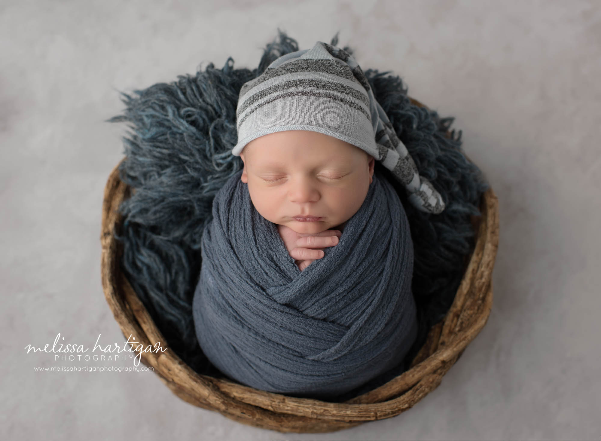 newborn baby boy wrapped in navy blue with blue and gray sleepy cap CT newborn photography session