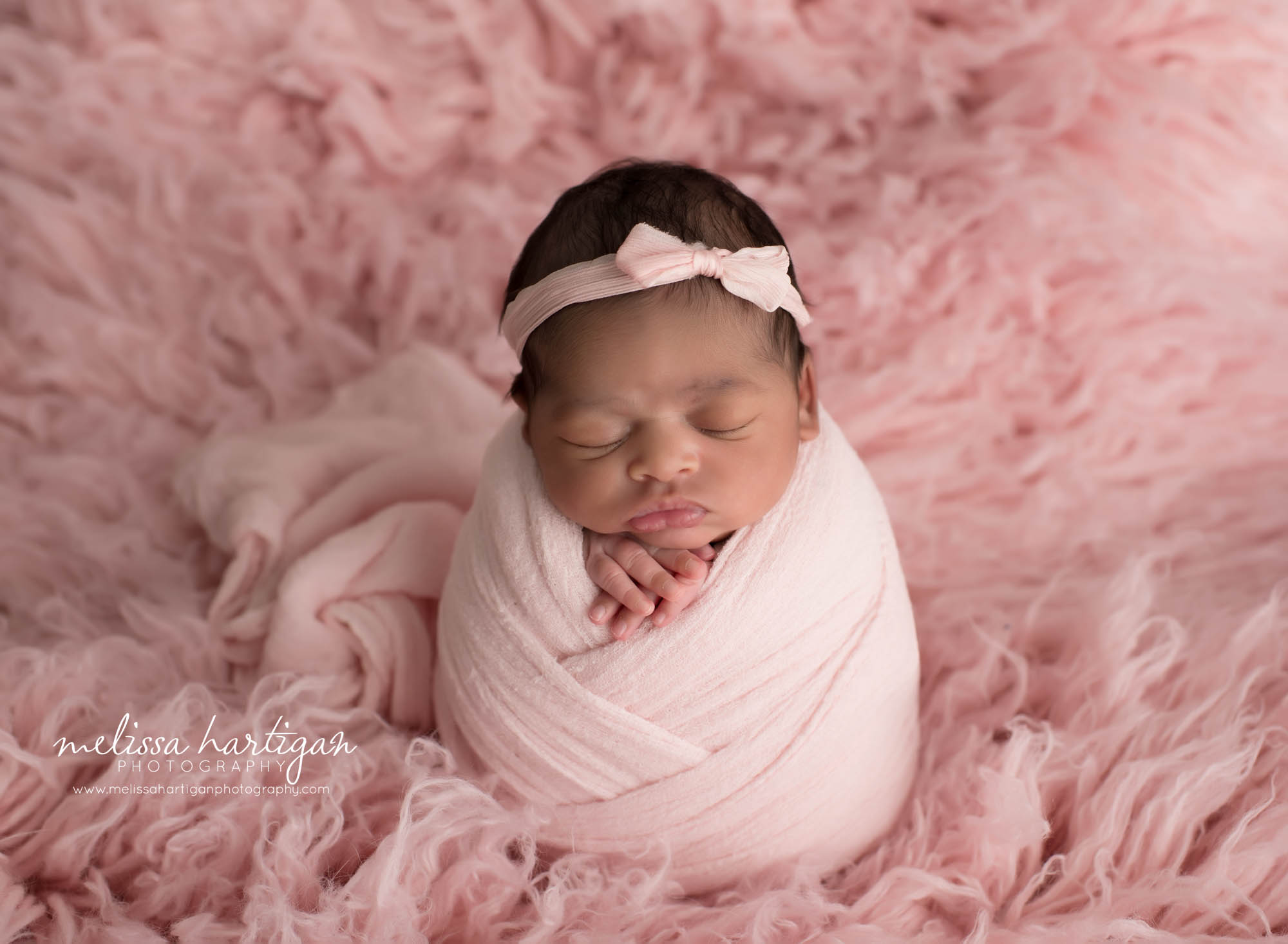 baby girl wrapped in pink wrap with bow headband pose don pink flokati rug fur