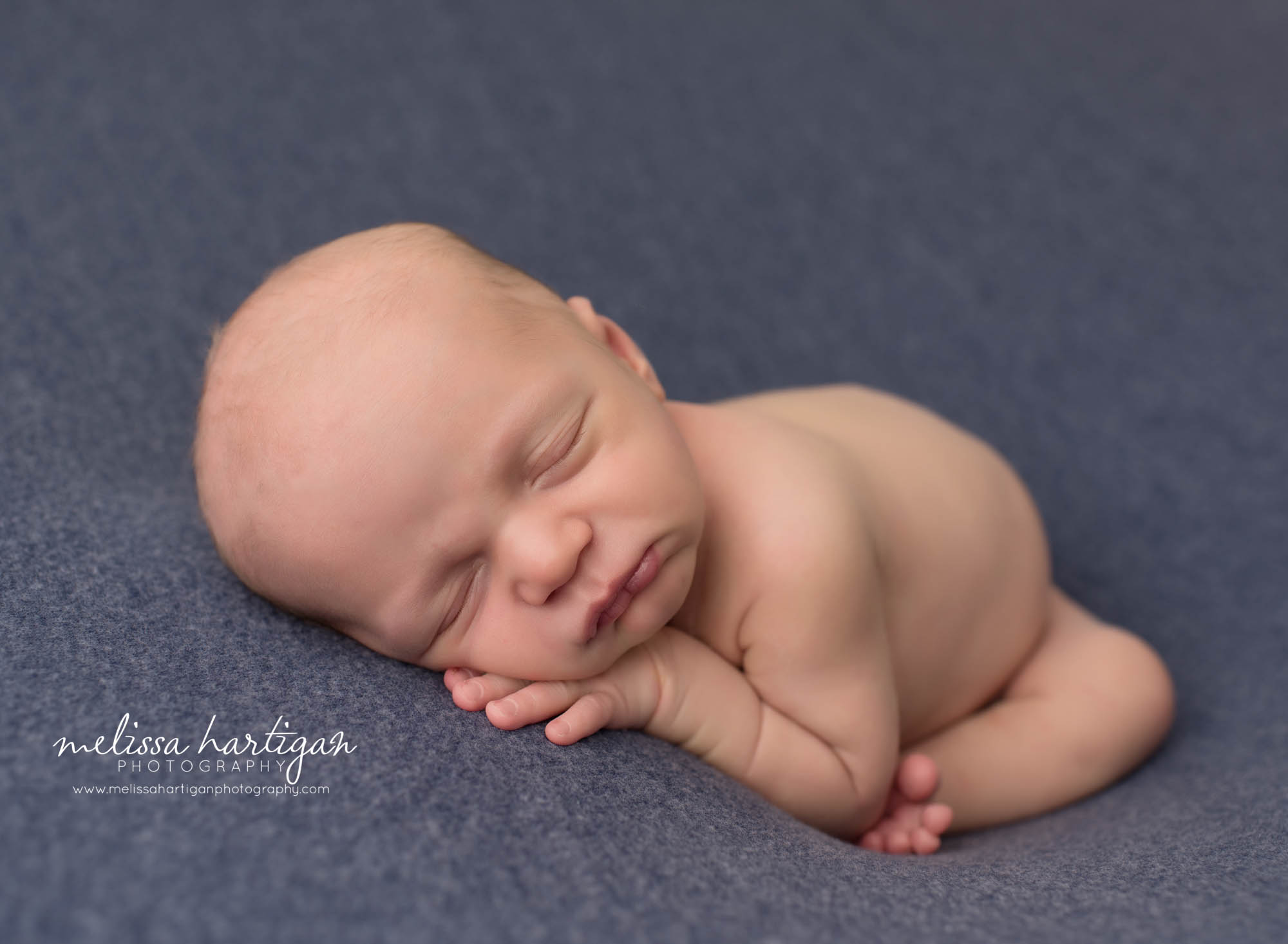 sleeping baby boy posed on blue backdrop with hand under cheek