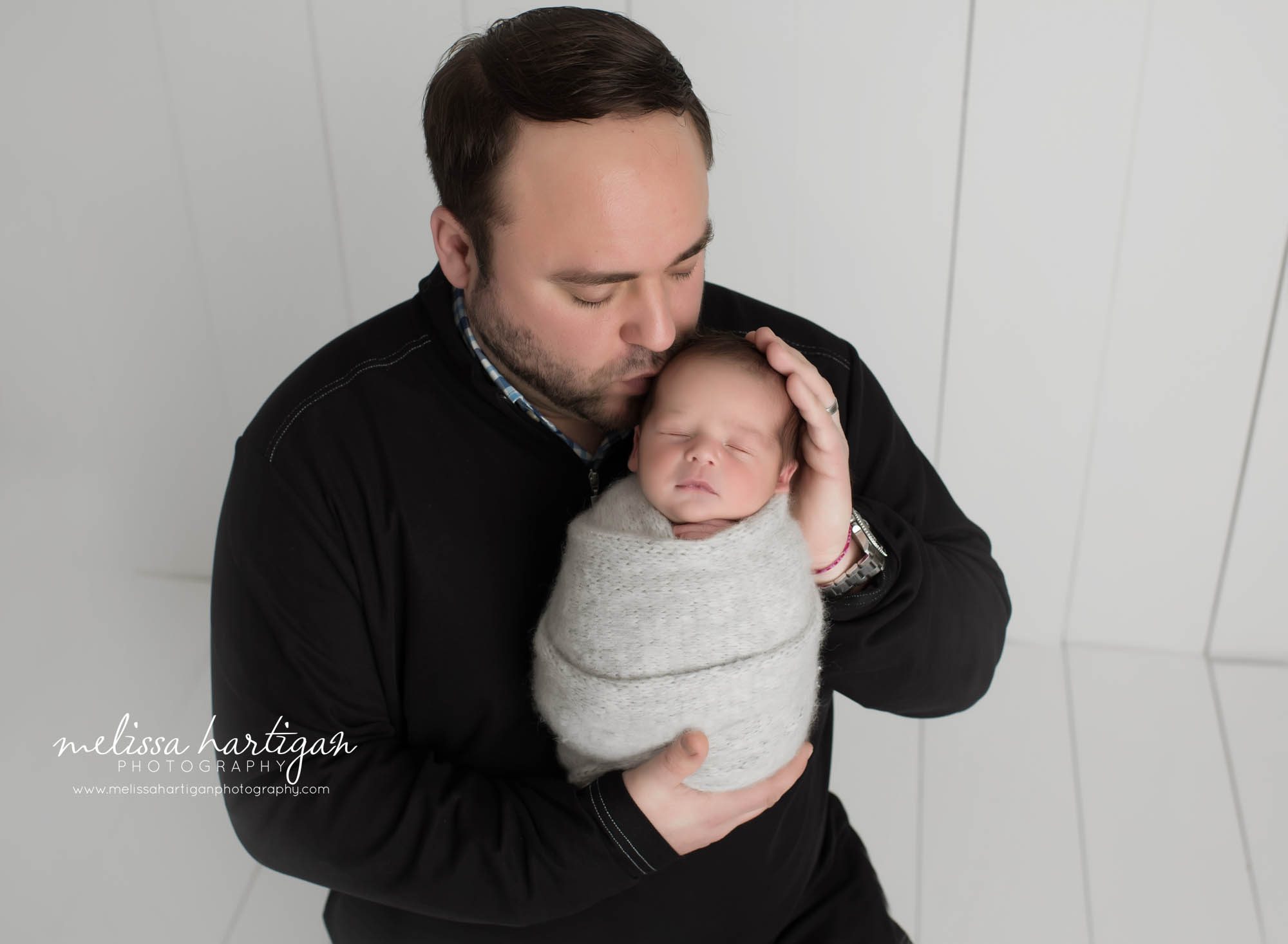 Dad holding newborn baby boy kissing him on head parent photo Newborn session