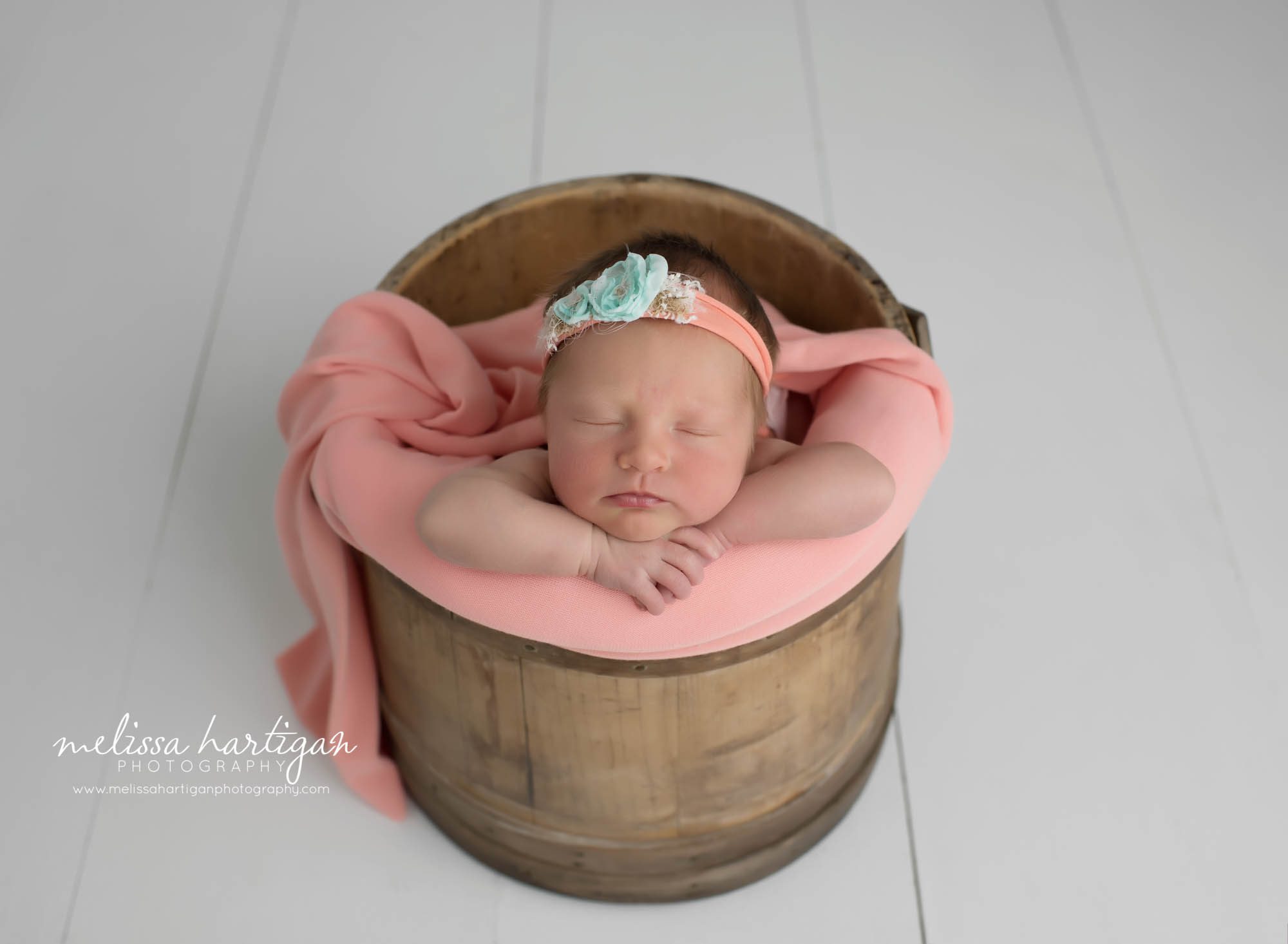 Newborn baby girl posed in wooden prop bucket with coral wrap and coral headband Newborn baby photography CT