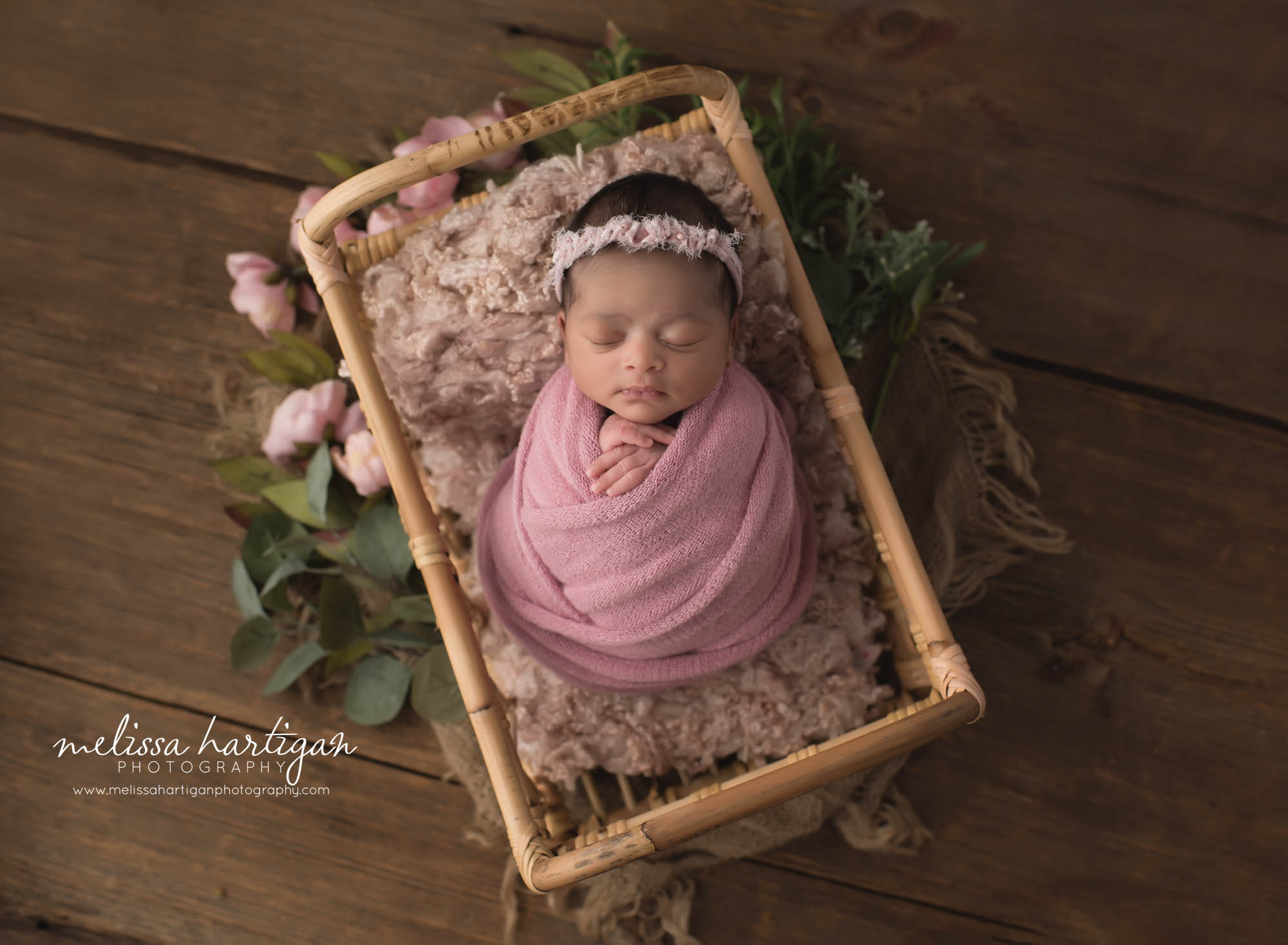 baby girl posed in wicker basket with pink wrap and pink headband Newborn Photographer Hartford County