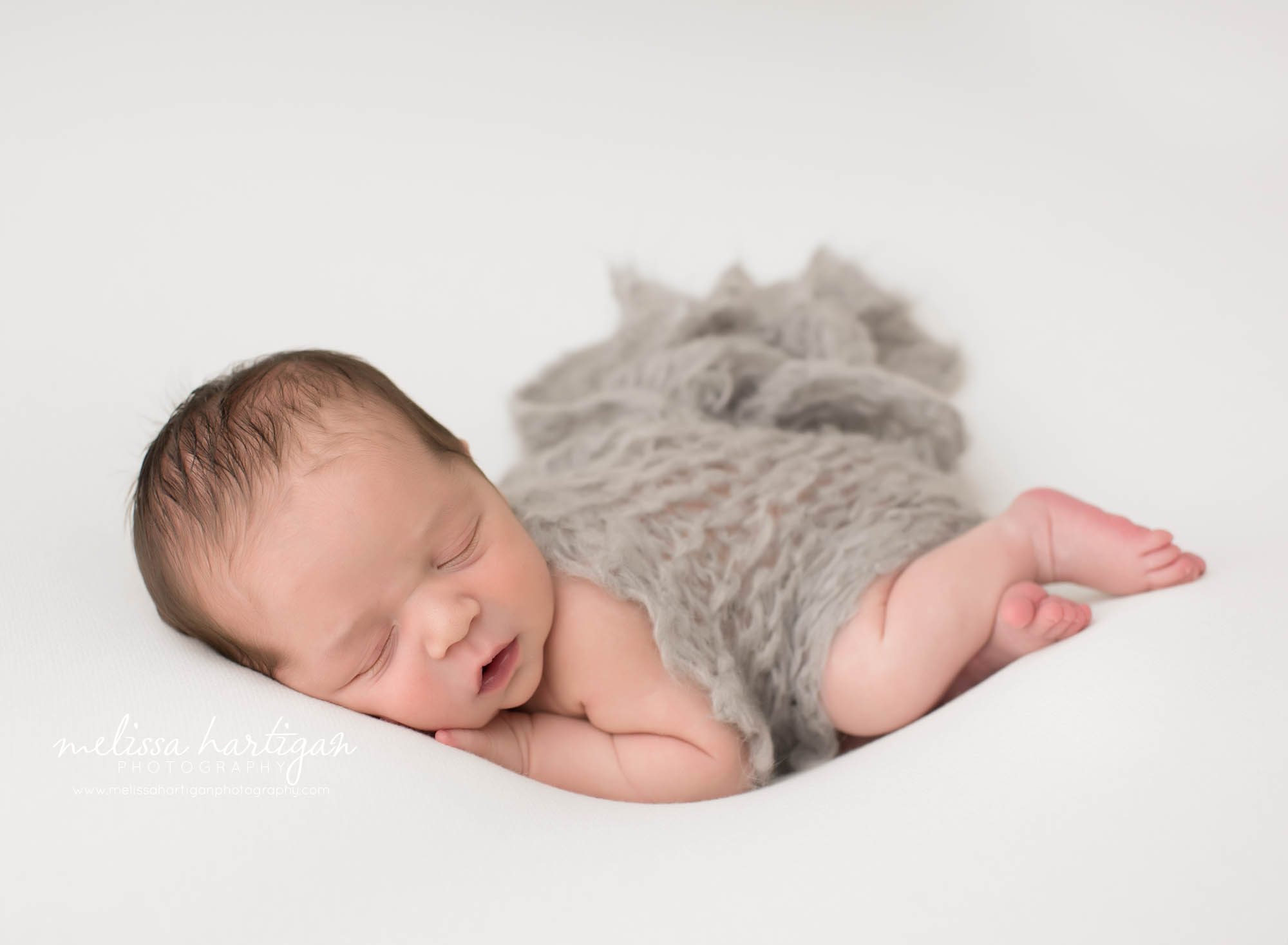 baby boy posed on side with light gray chunky knitted layer draped over