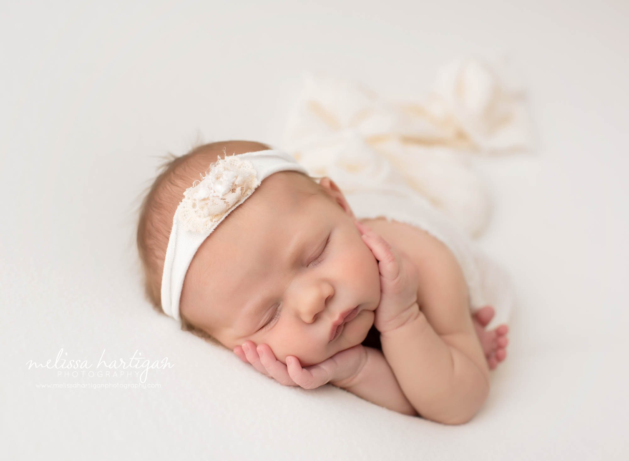 Newborn baby girl posed on white backdrop with ivory headband Mansfield CT Baby photographer