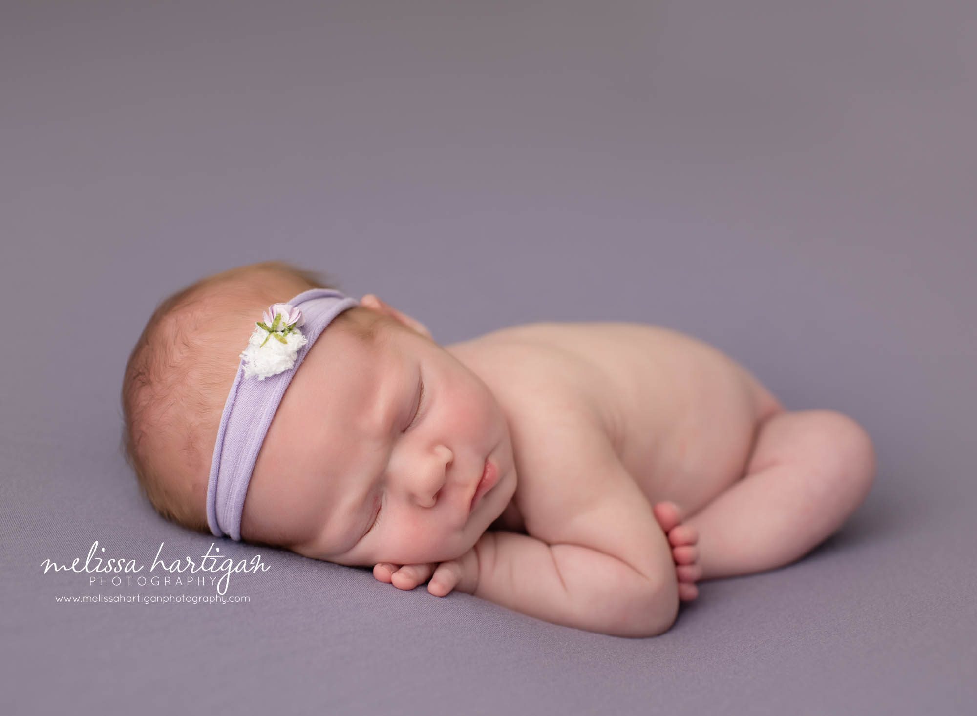 Newborn baby girl posed modified taco pose on purple backdrop and purple headband Newborn Photographer CT Vernon