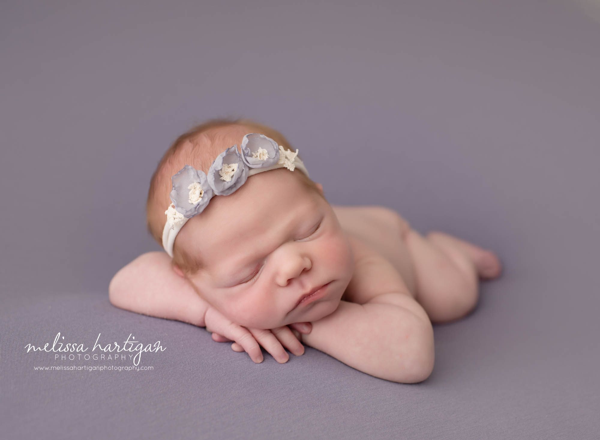 newborn baby girl posed on tummy with head on hands flower headband Newborn Photographer Vernon CT