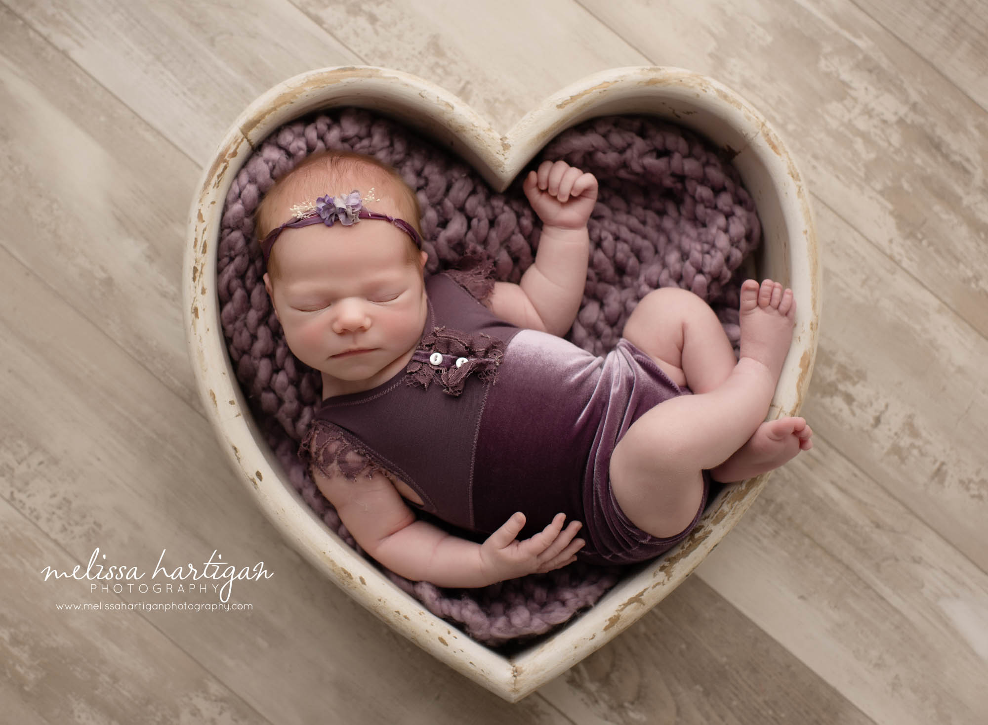 newborn baby girl posed in white wooden heart prop with purple layer and purple outfit with matching purple headband Newborn Photography Connecticut