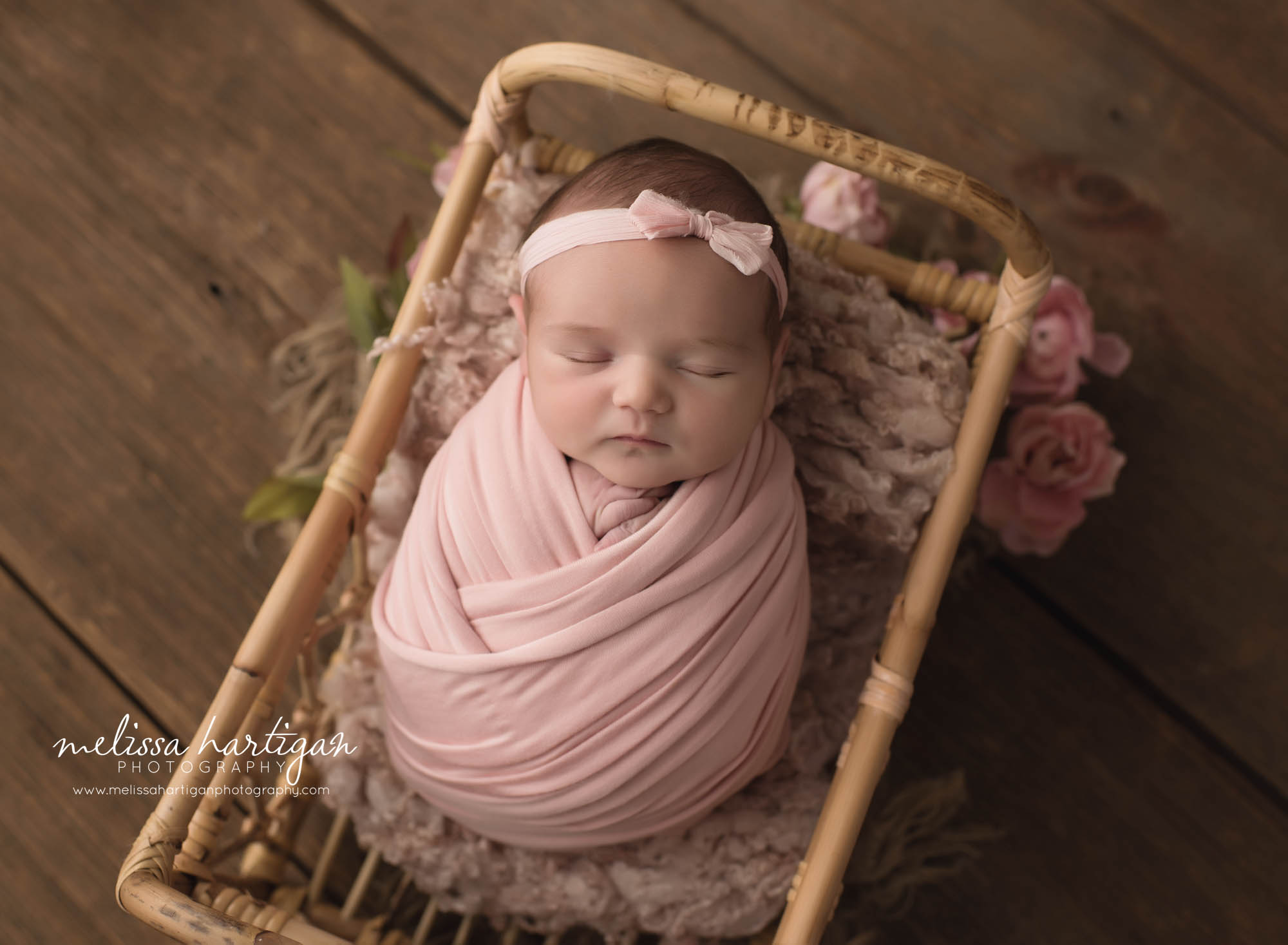 Newborn baby girl wrapped in pink wrap posed in basket with lgith pink lay and flowers Rocky Hill Newborn Photography