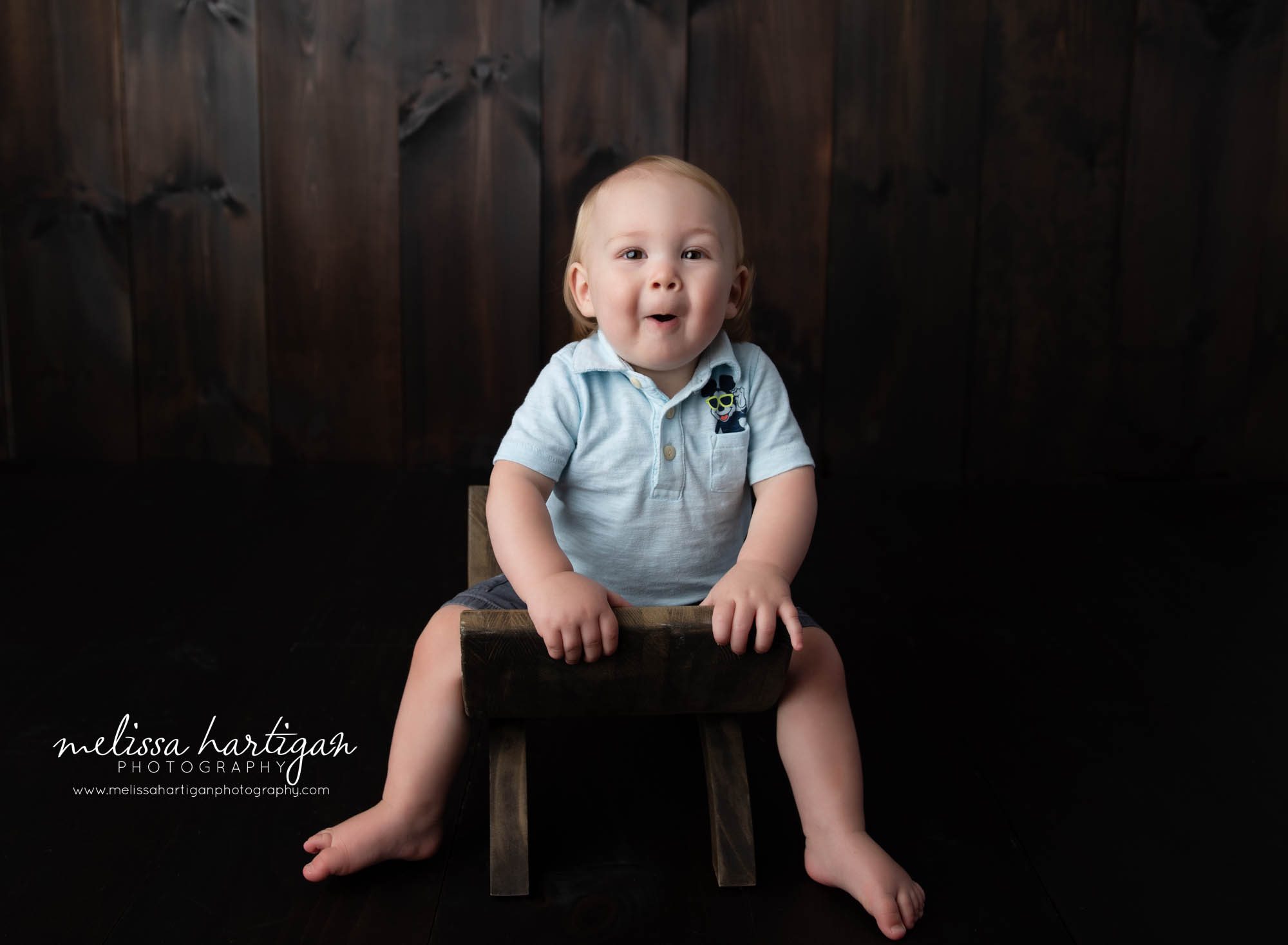 baby boy sitting on wooden stool on photography studio