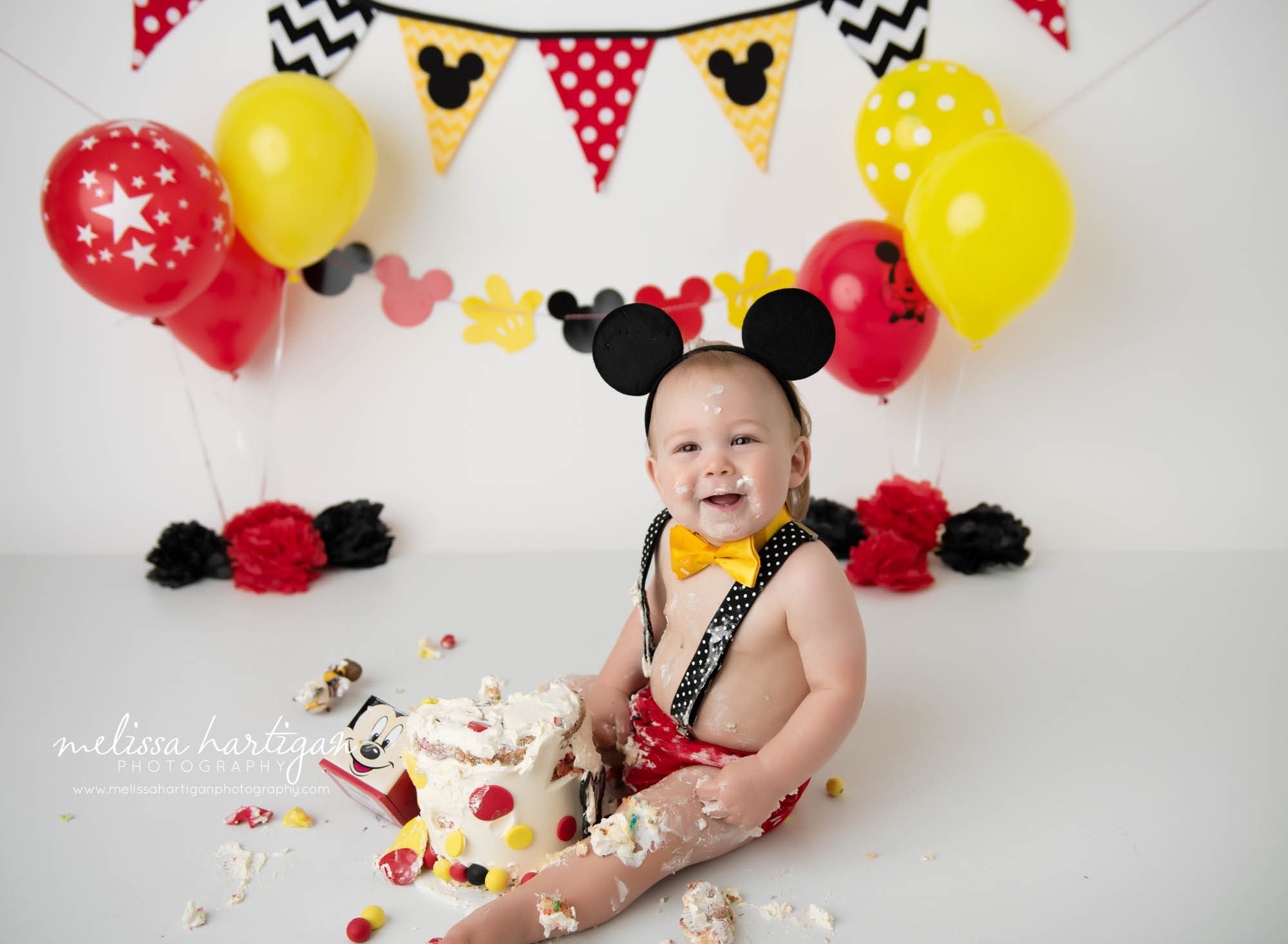 baby boy sitting on floor with destroyed mickey mouse cake smash Ct baby photography cake smash