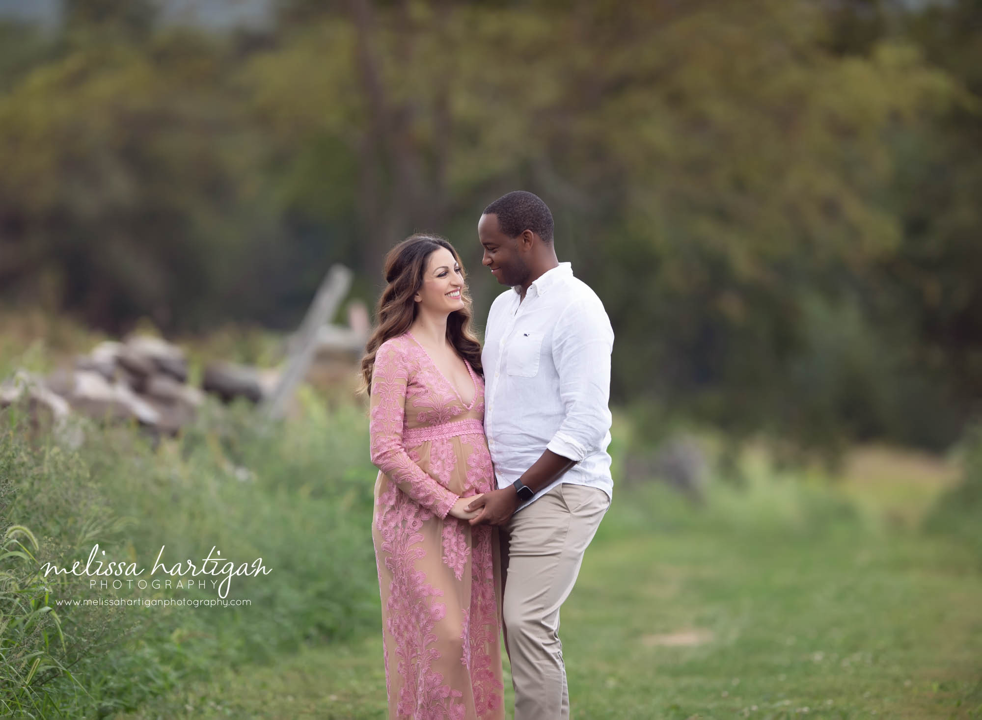 mama to be and dad to be holding hands looking at each other outside maternity photorgaphy session CT maternity photographer