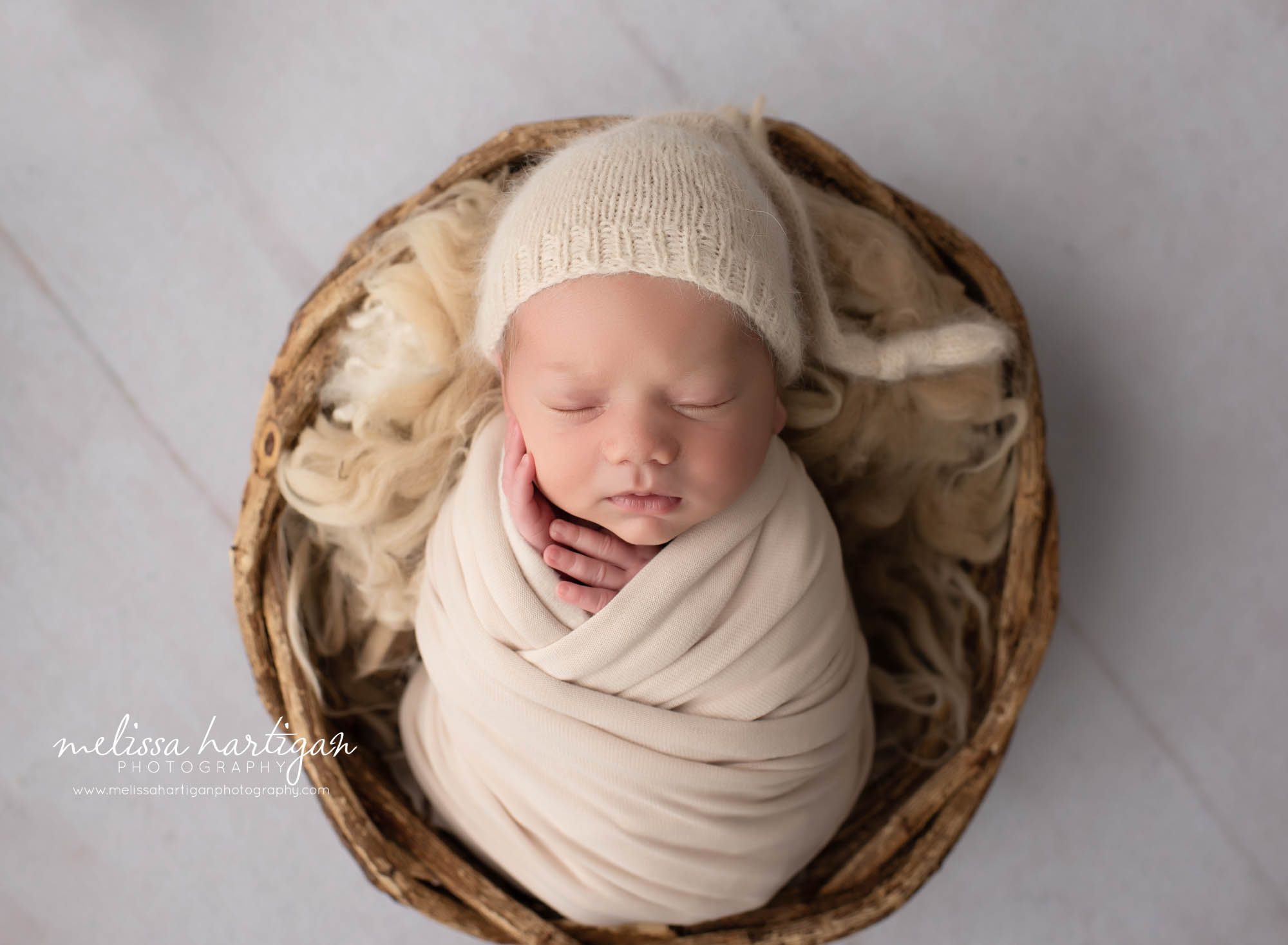 newborn baby boy wrapped in beige wrap with knitted beige sleepy cap posed in basket CT newborn photographer