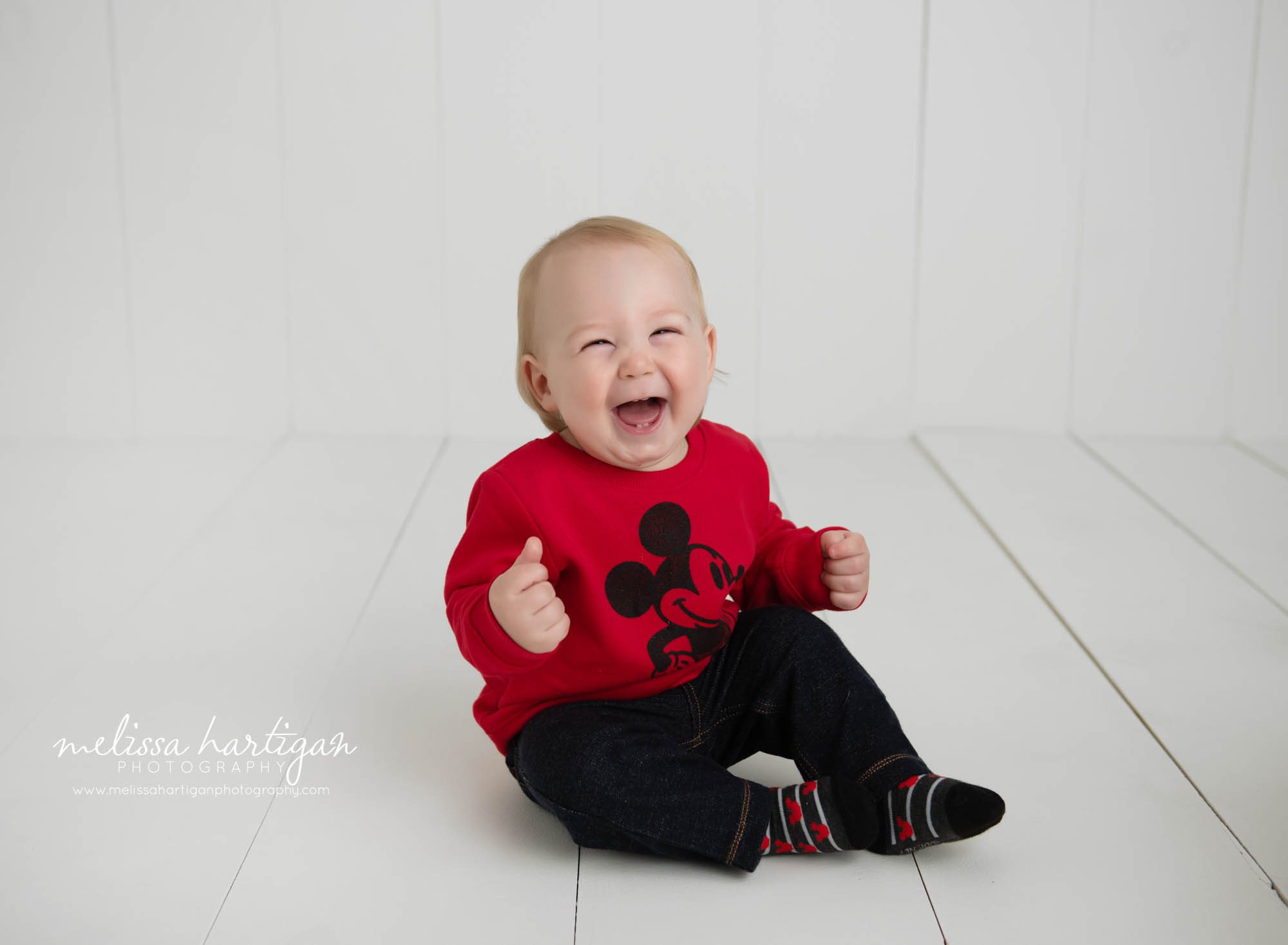 baby boy sitting on floor laughing in studio photography milestone session
