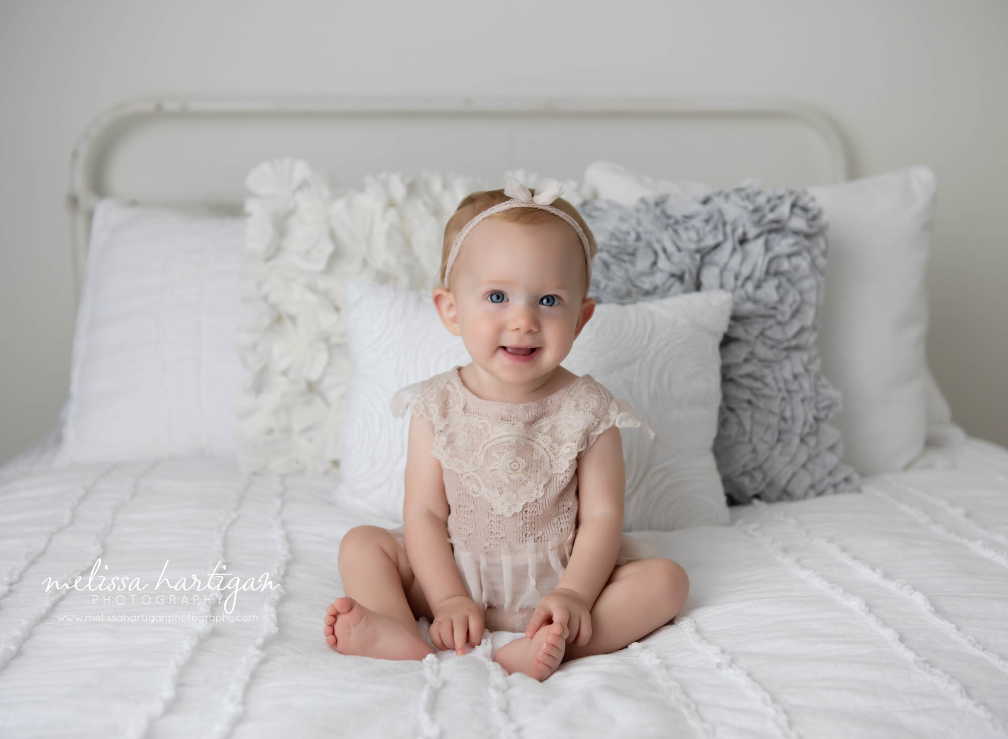 baby girl sitting on bed smiling at camera CT baby photography