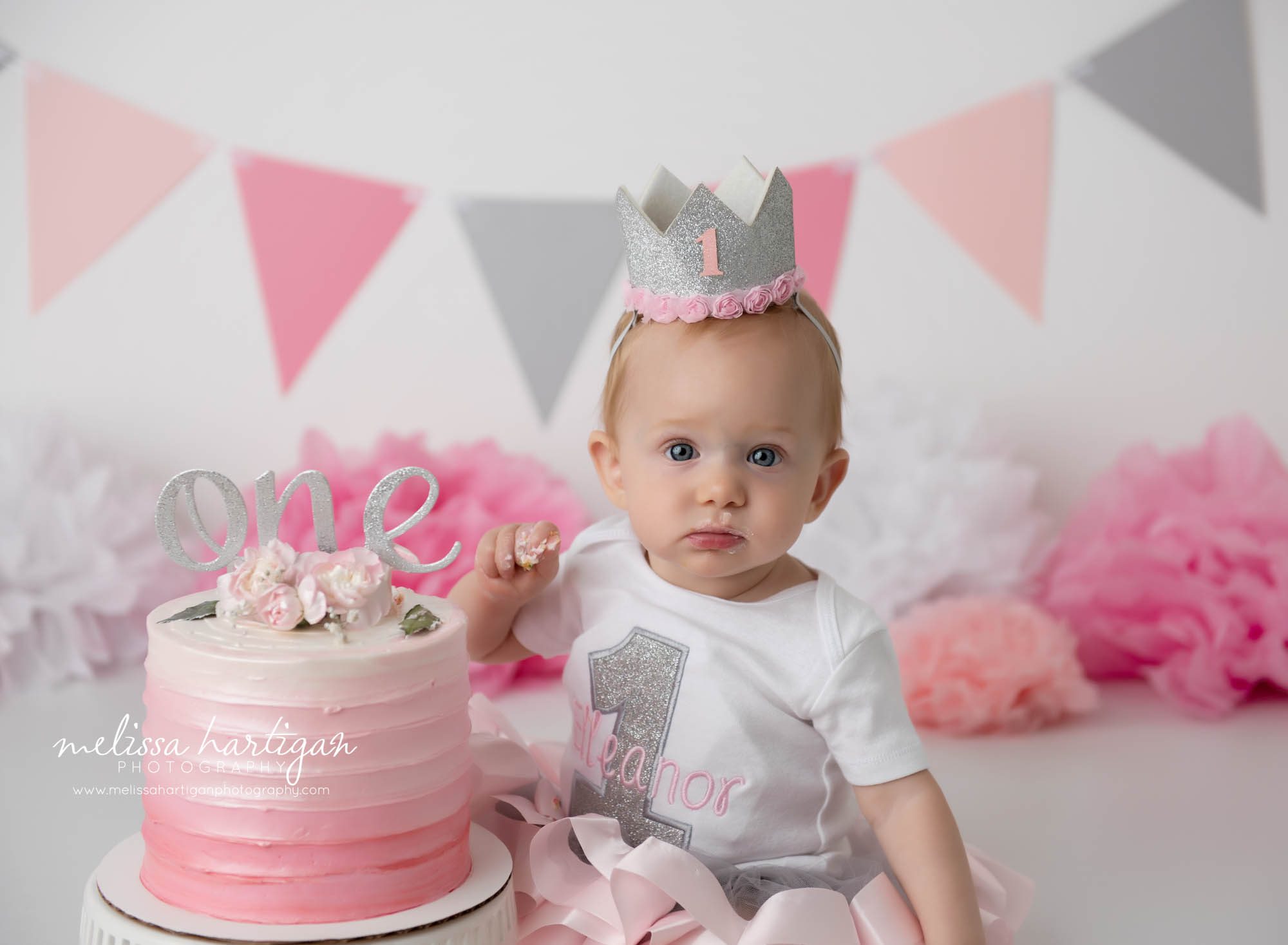 baby girl looking at camera after getting into cake from cake smash