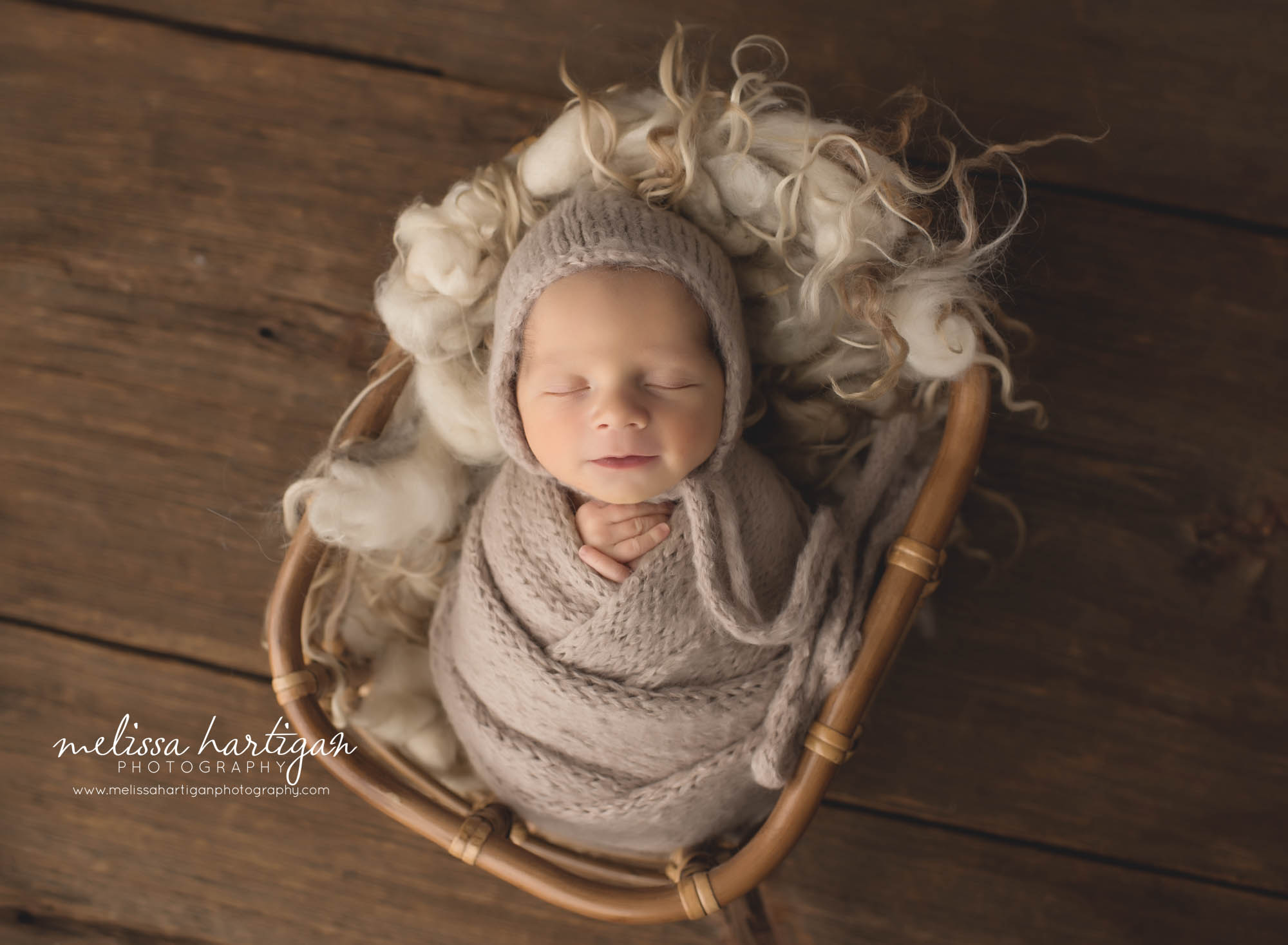 Newborn baby boy wrapped in knitted wrap with matching bonnet basket with curly layers