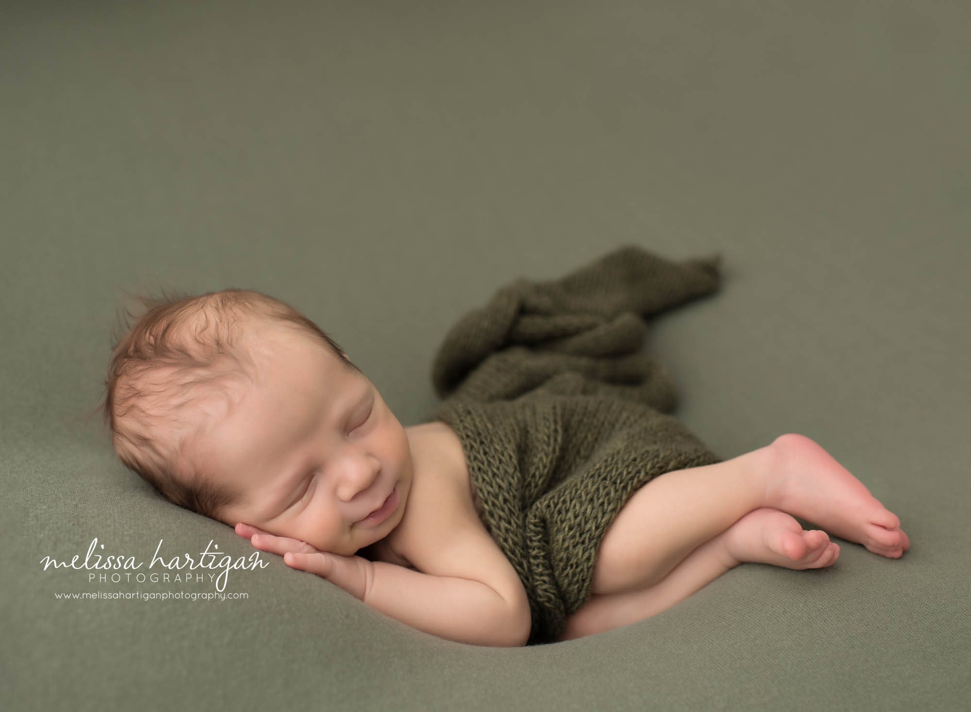 Baby boy posed on side wiht knitted green wrap on green backdrop Norwich CT Baby photography