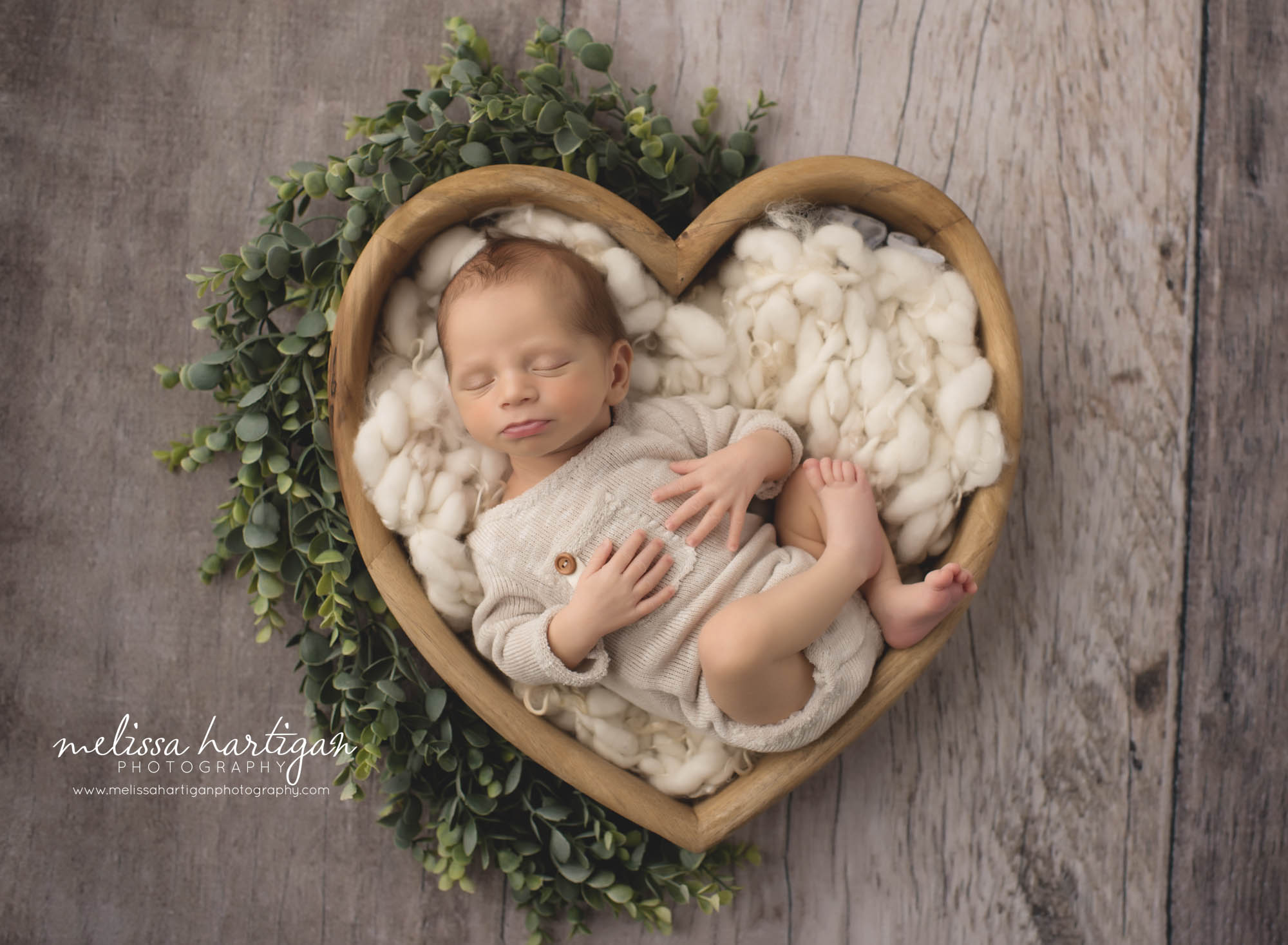 baby boy posed on back in wooden heart prop