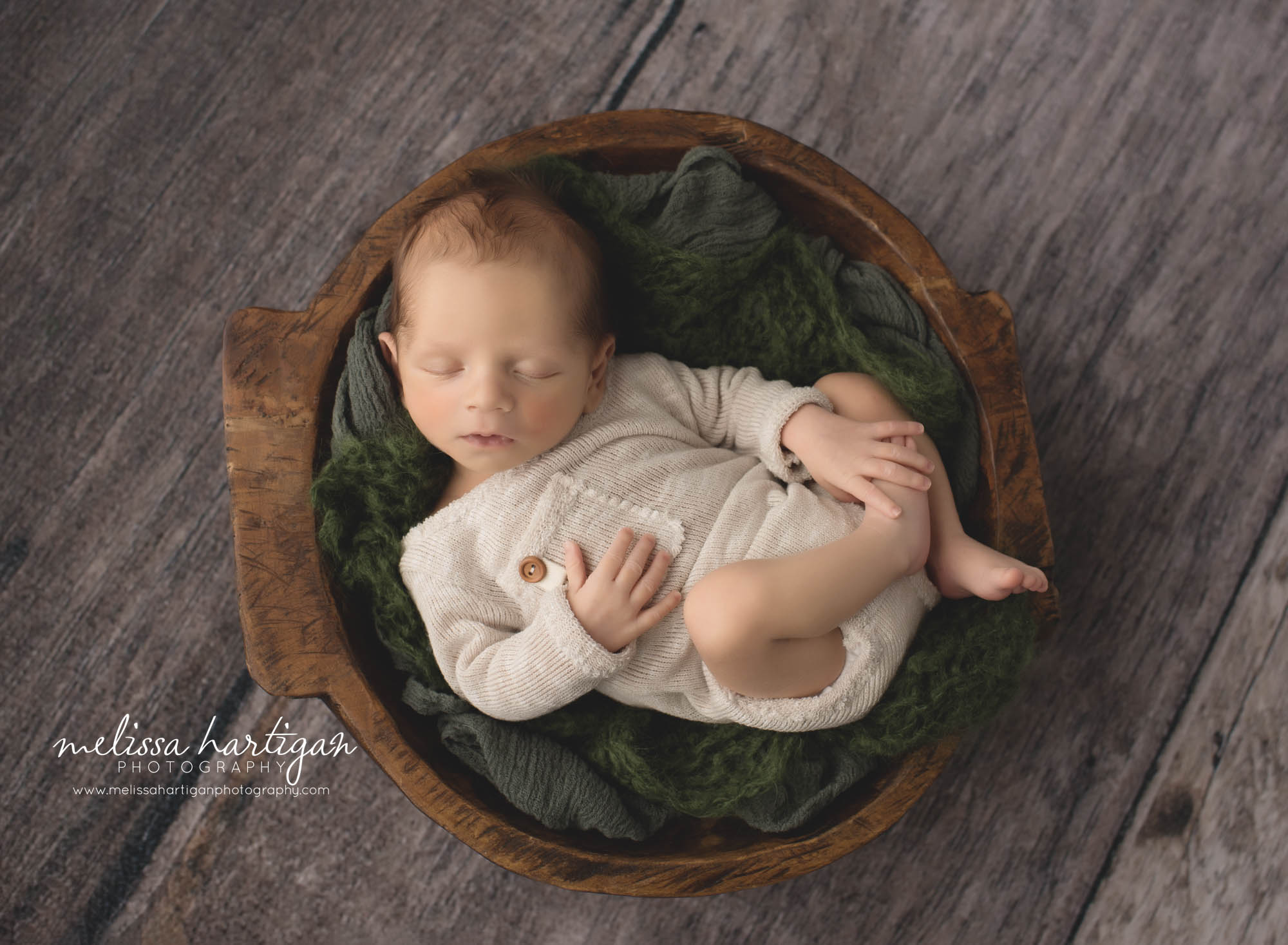 newborn baby boy posed on back with forest dark green layers