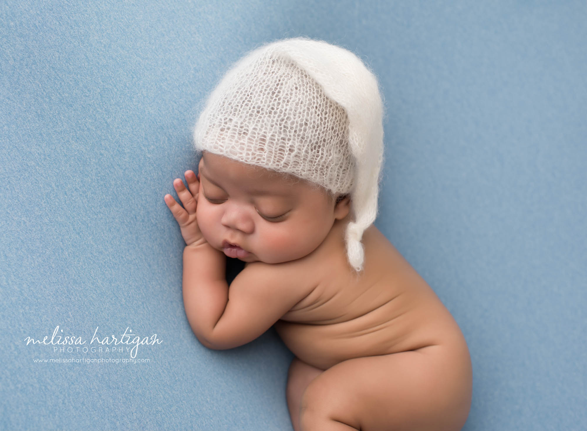 Baby boy posed on side with cream knitted sleepy cap newborn photography connecticut