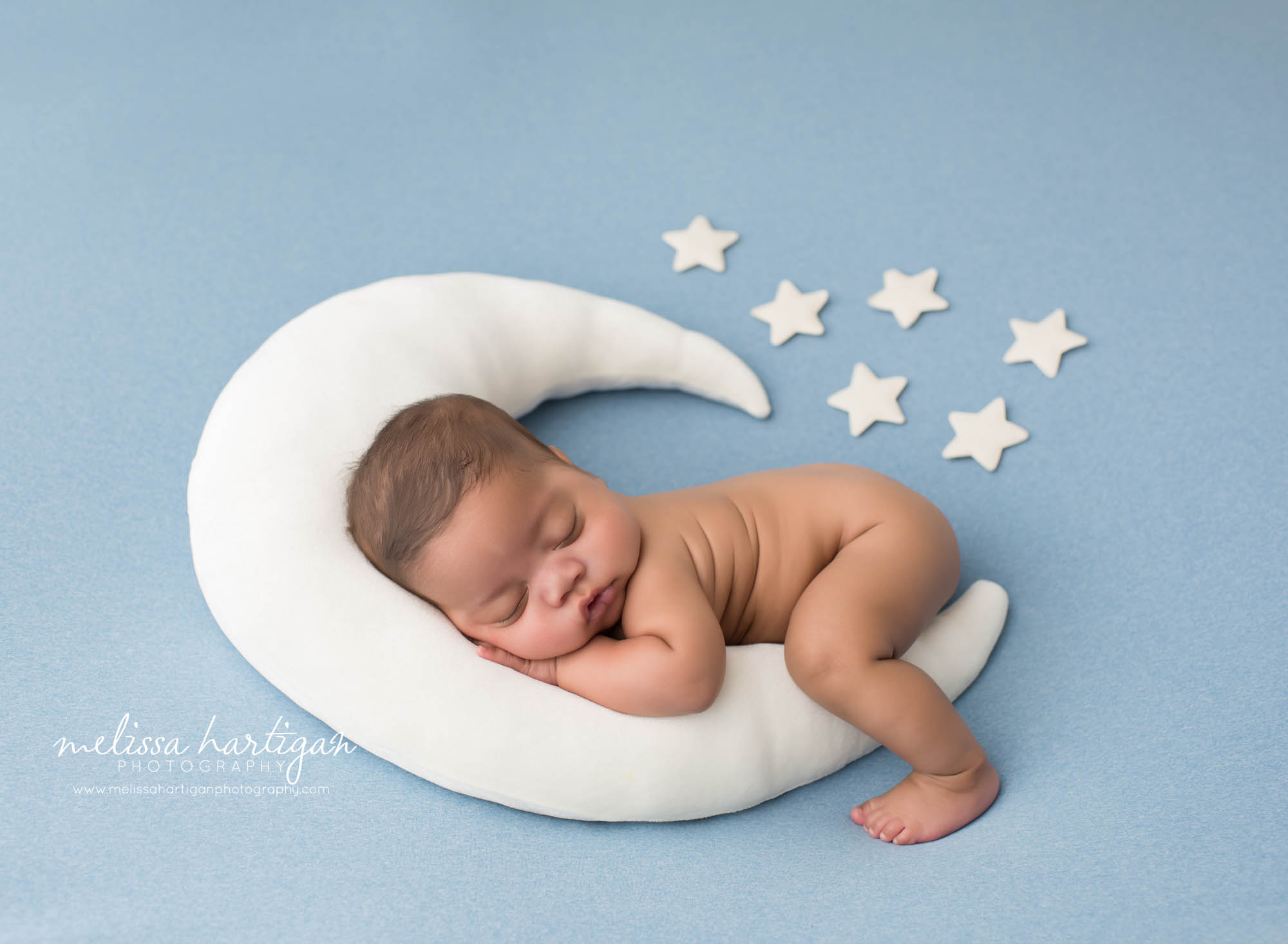 baby boy posed on moon pillow prop with white stars on blue backdrop studio newborn photography north haven CT
