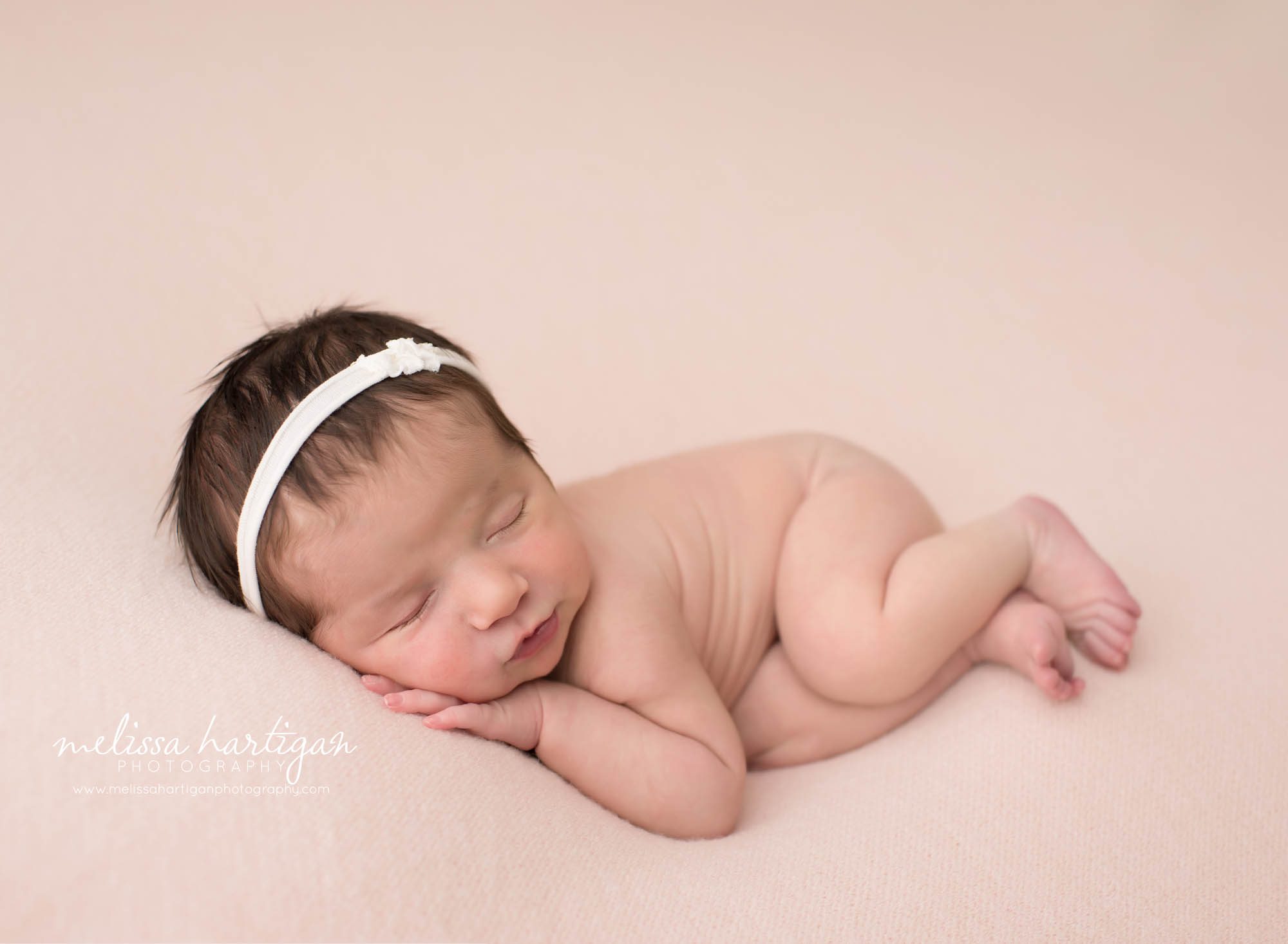 baby girl posed on side with cream flower headband