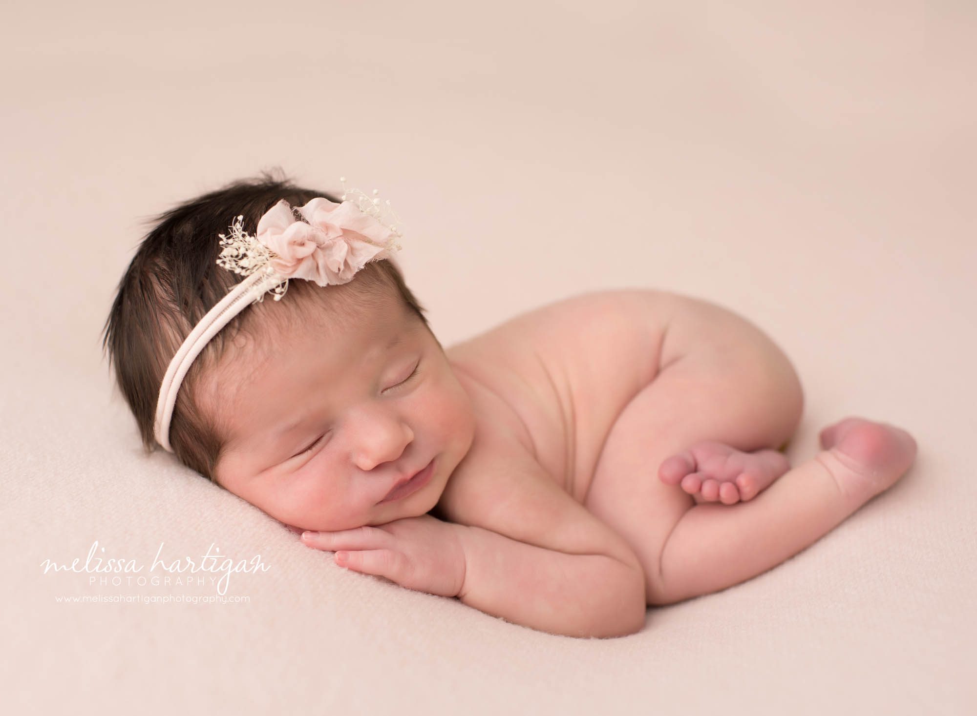 baby girl posed on side with light pink bow headband