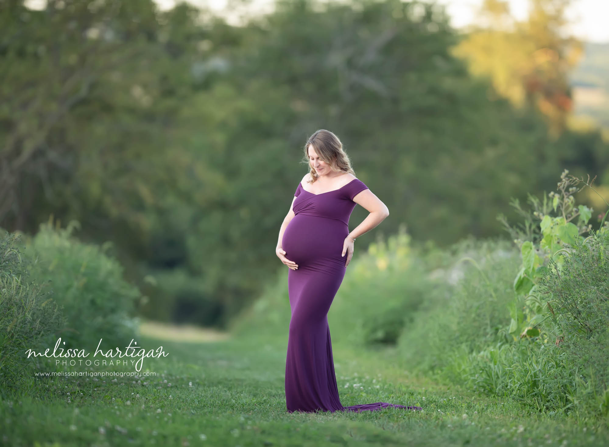 pregnant mom to be holding baby bump looking down at baby belly