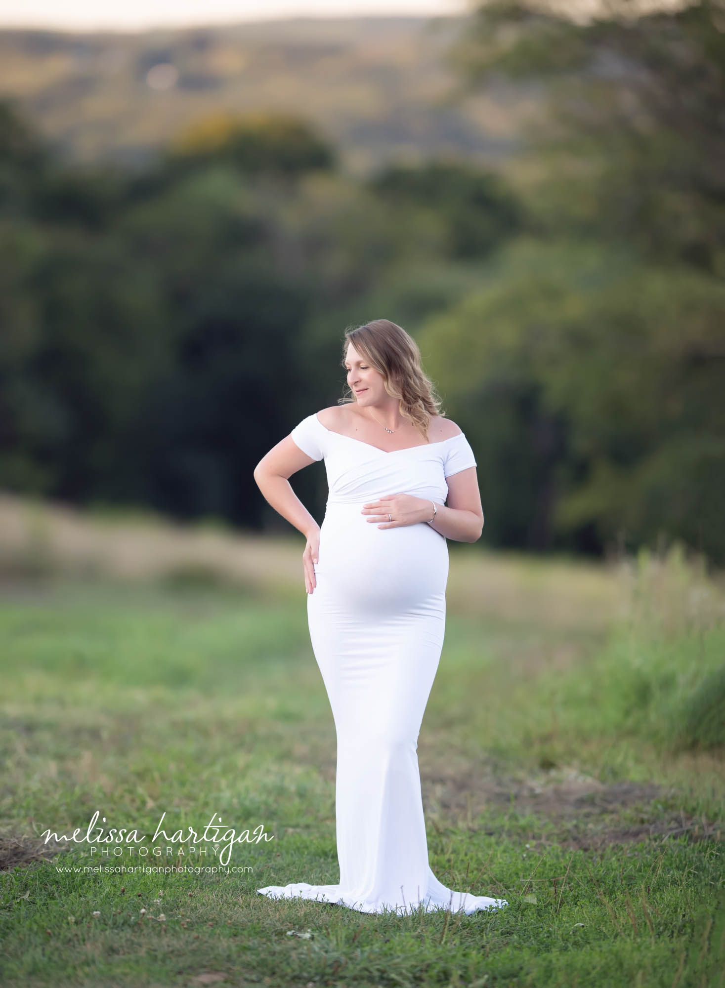 mama to be pregnant holding baby bump wearing long form fitted white maternity gown south windsor CT maternity photography