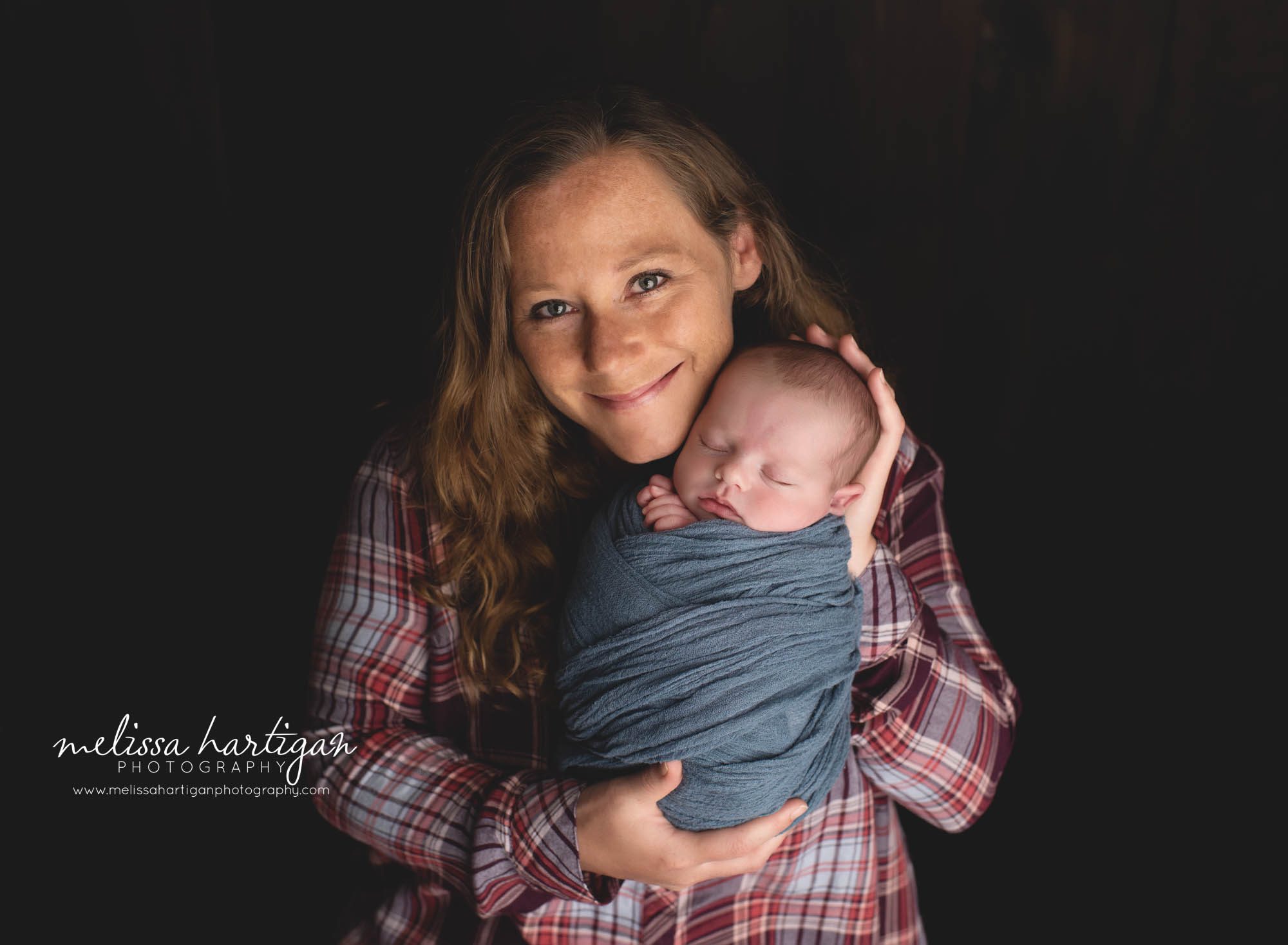 mom holding newborn baby boy wrappe din navy blue wrap Newborn Photography CT