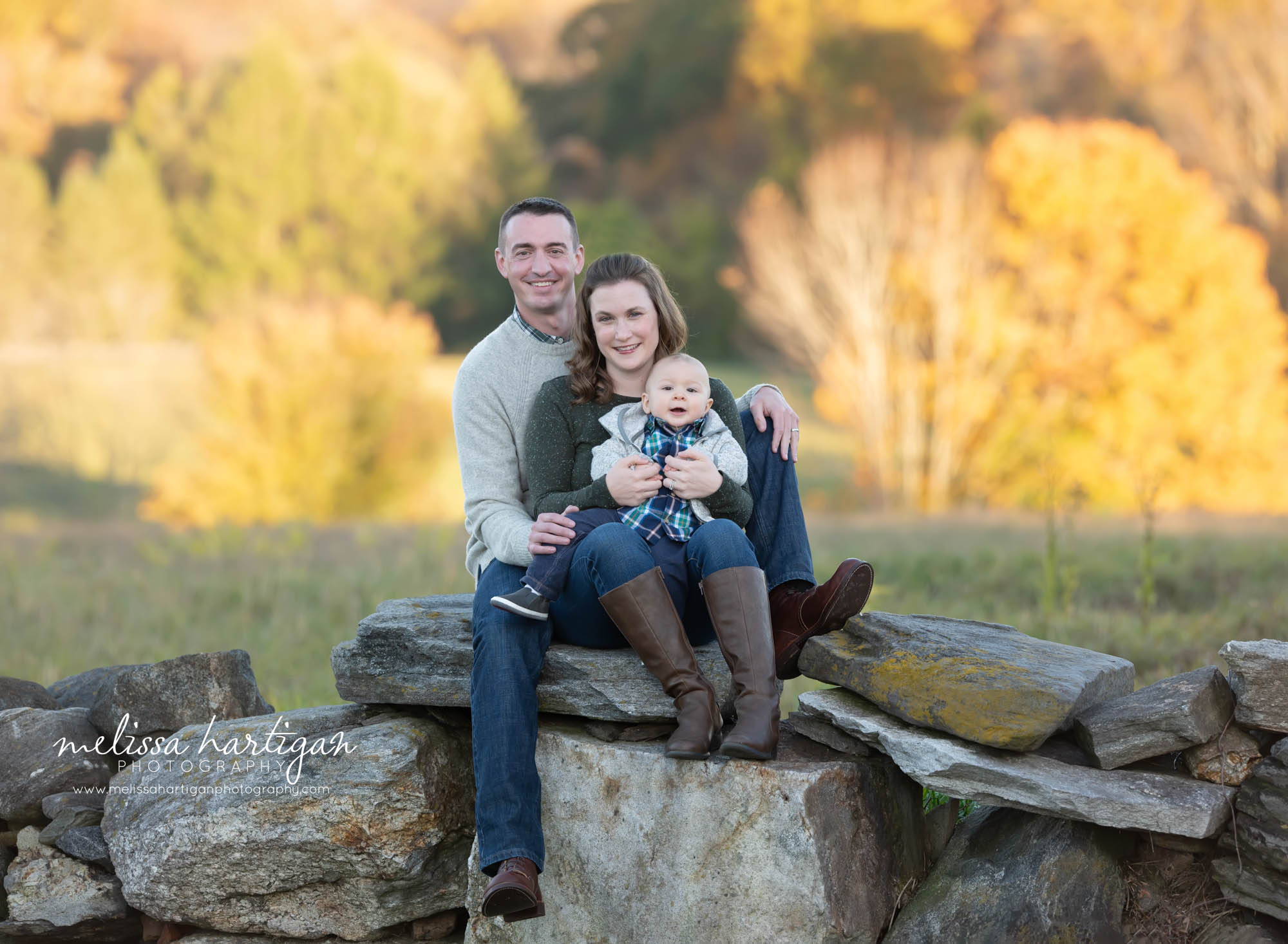 mom dad baby boy sitting on rock wall family photography outdoor on location CT park