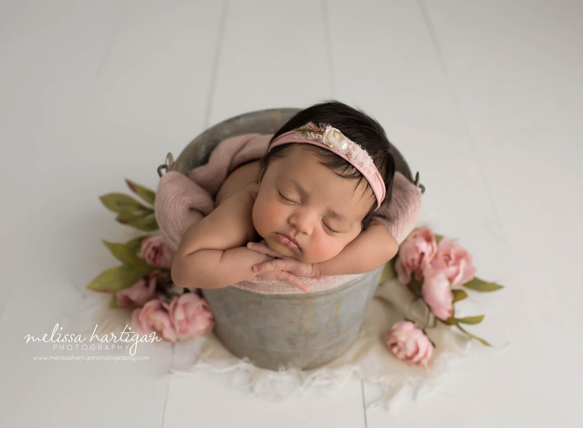 newborn baby girl posed in metal bucket with headband and flower elements hartford country CT Baby photographer