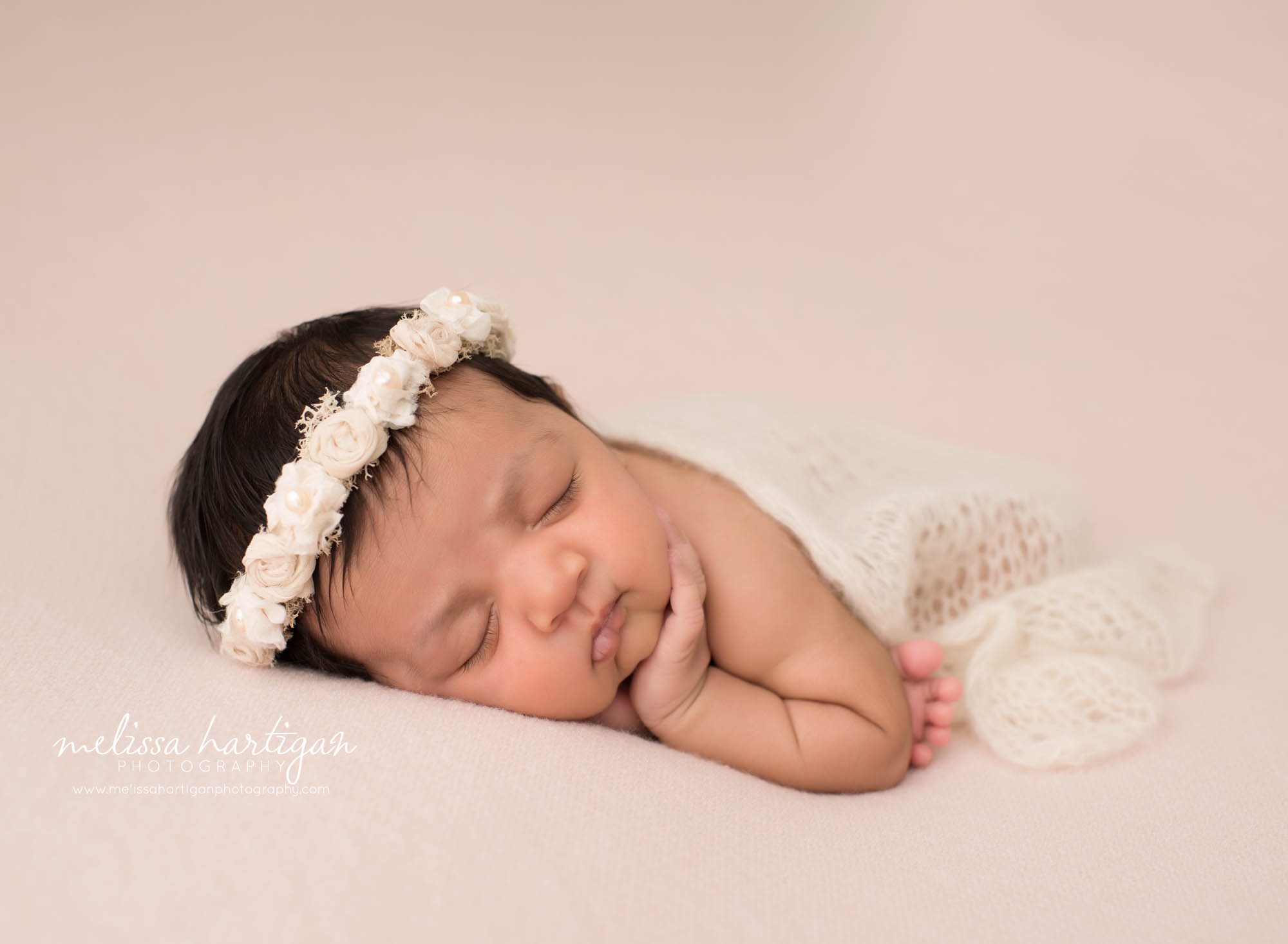 baby girl posed on pink backdrop with cream flower headband and draped layer