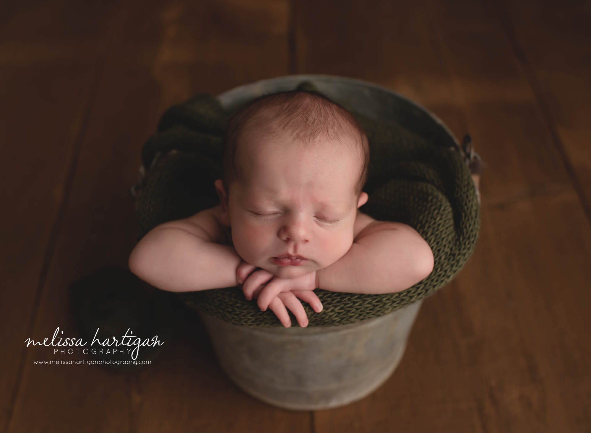 baby boy posed in metal bucket with green knitted wrap