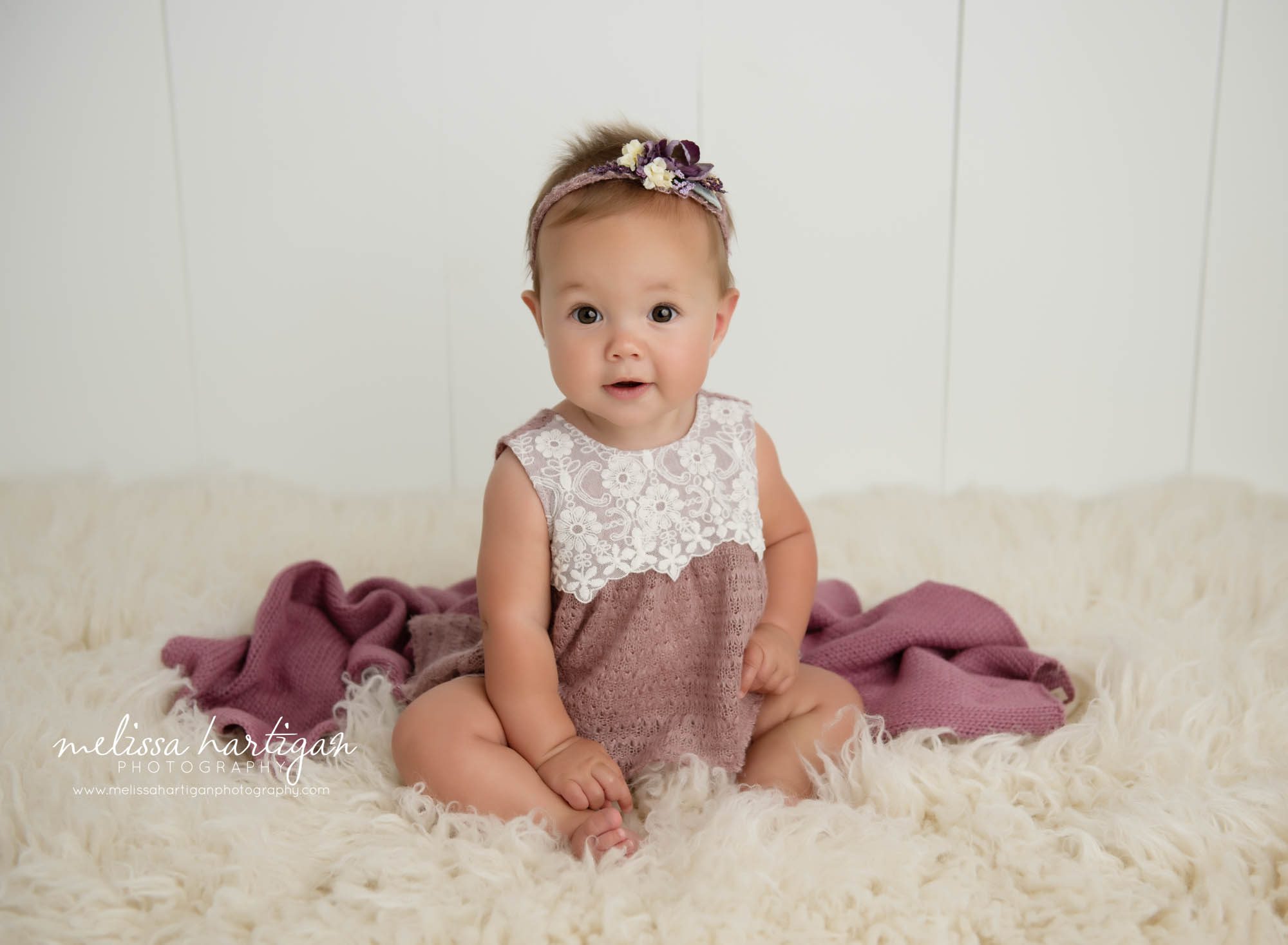 baby girl sitting on rug with pink and cream outfit