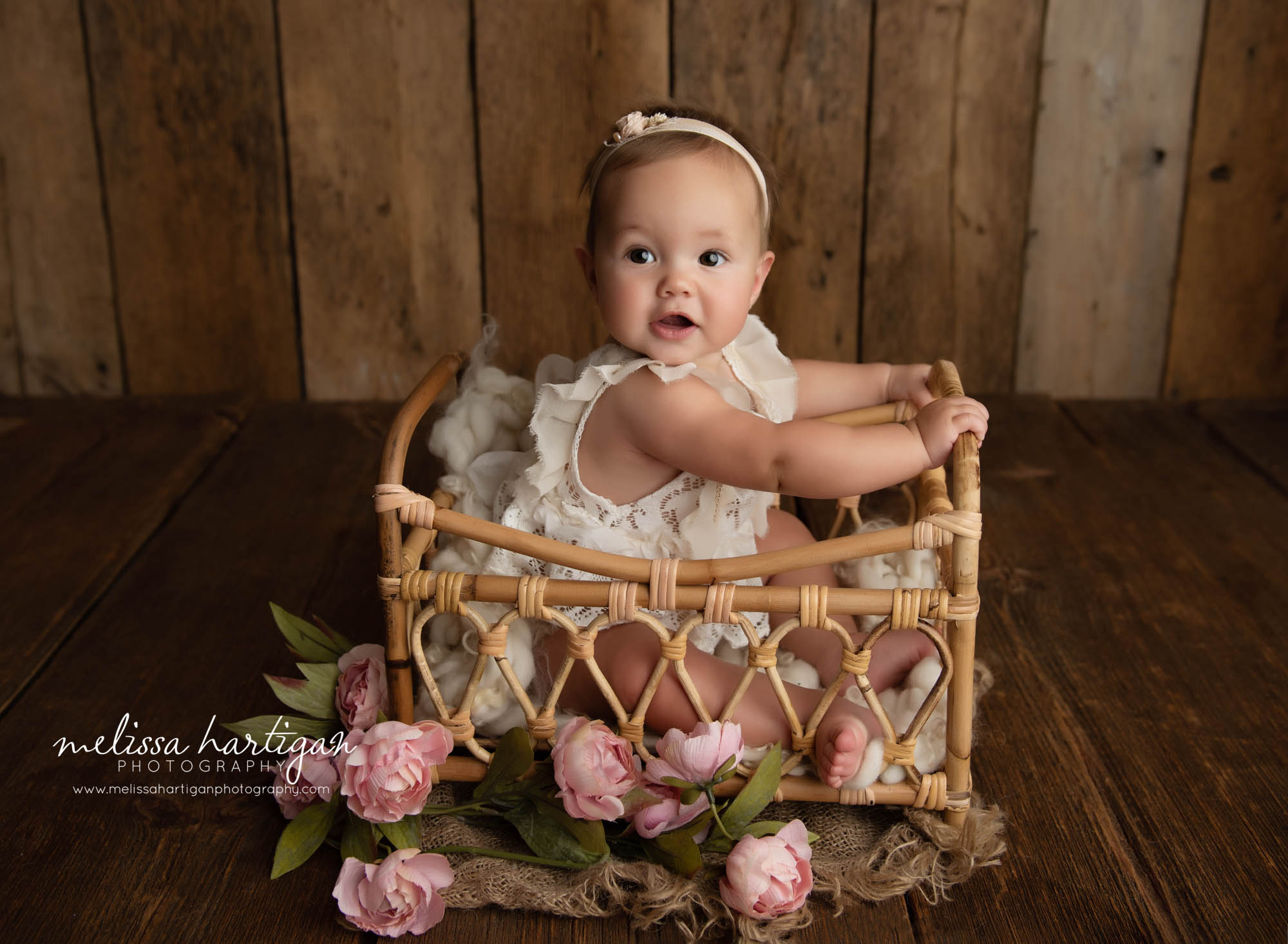baby girl sitting in basket with flowers