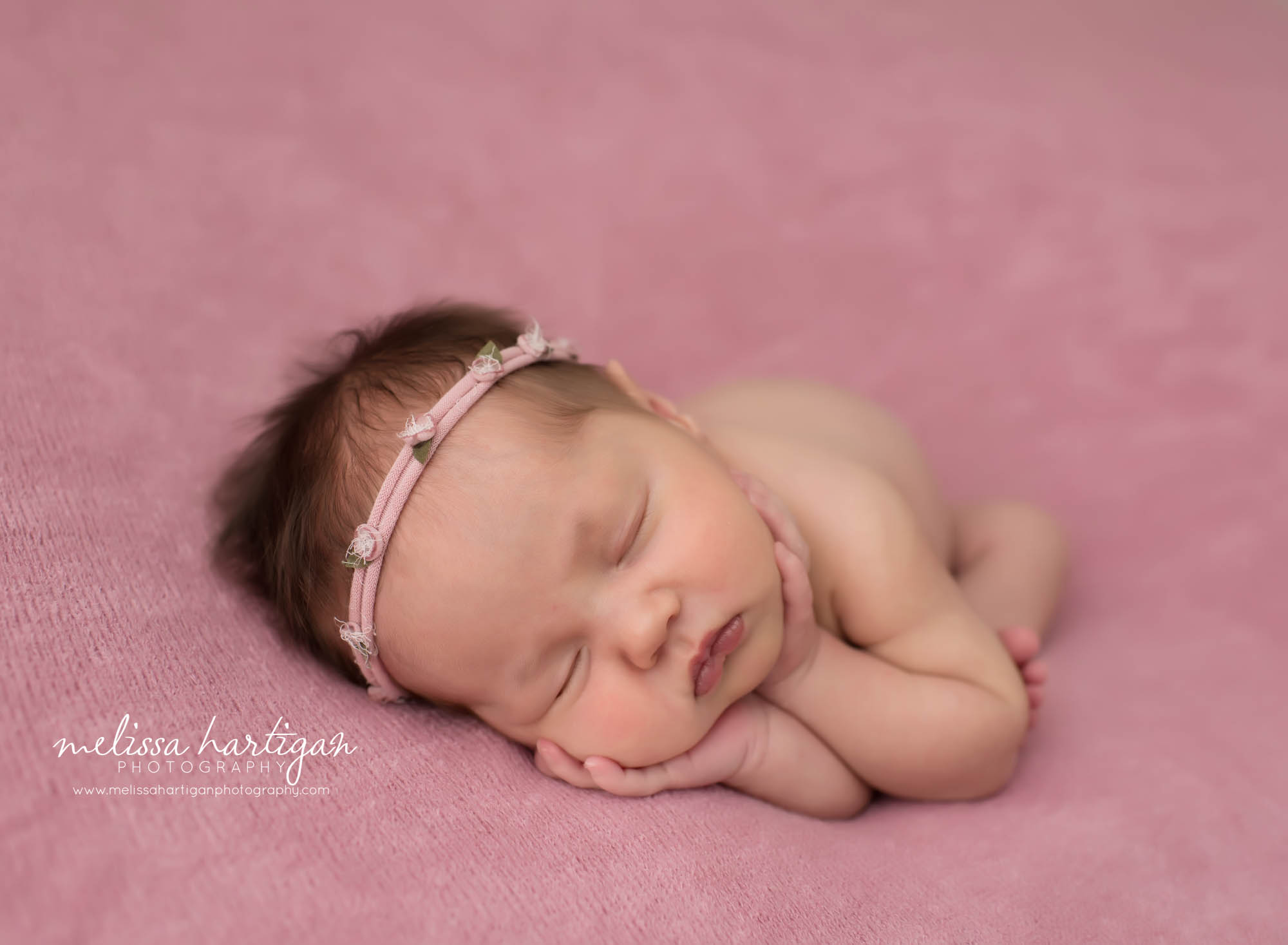 newborn baby girl posed on side pink flower headband