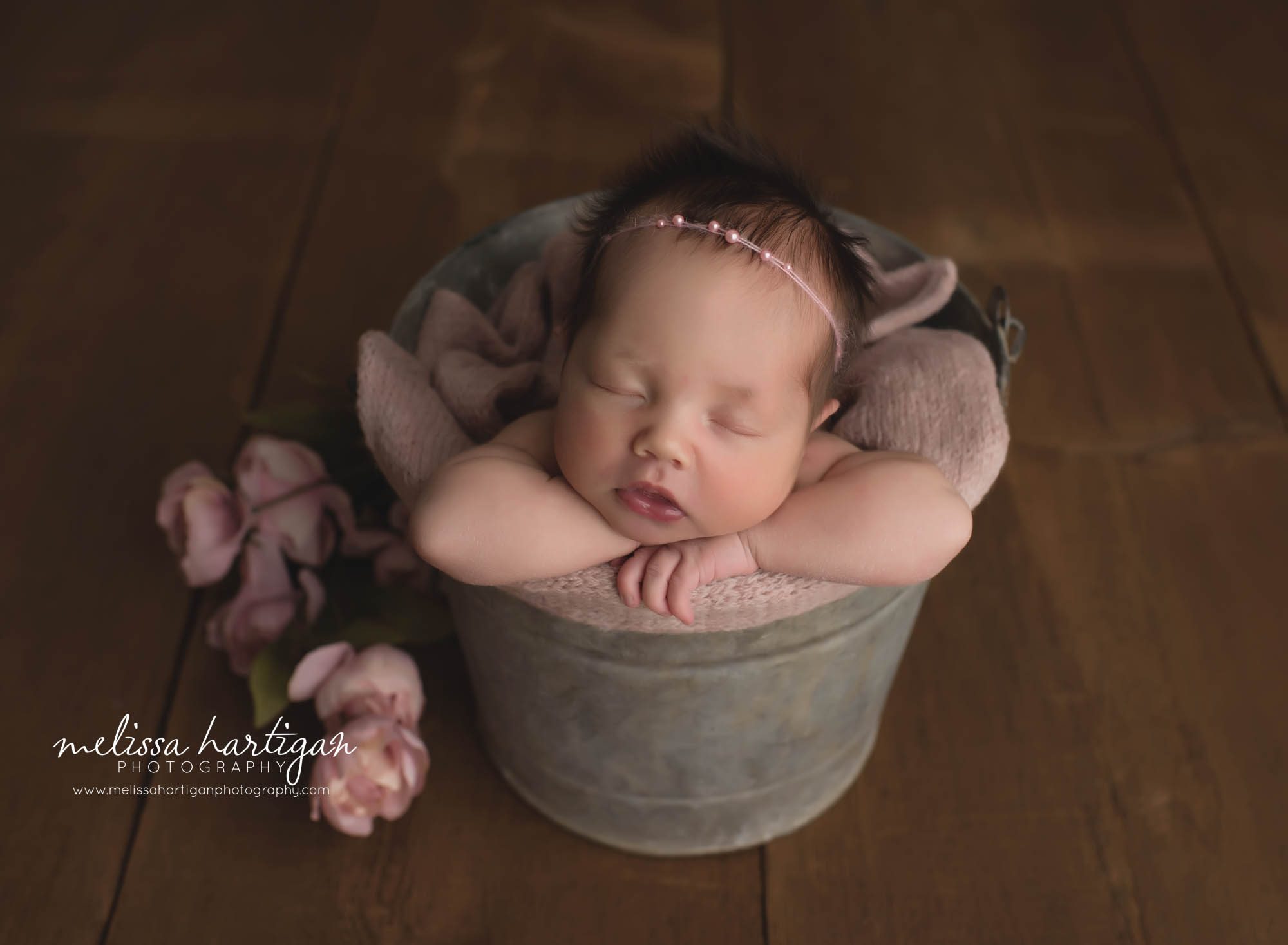newborn baby girl posed in bucket with flower elements